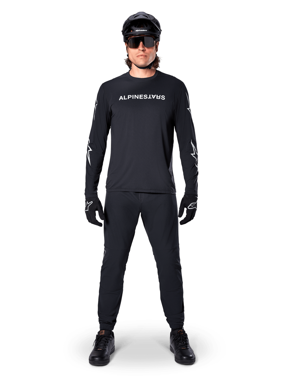 Alpinestars A-Dura Switch langærmet trøje, sort, båret af en mountainbikerytter med matchende sorte bukser og hjelm, hvidt logo på brystet, teknisk off-road cykelbeklædning