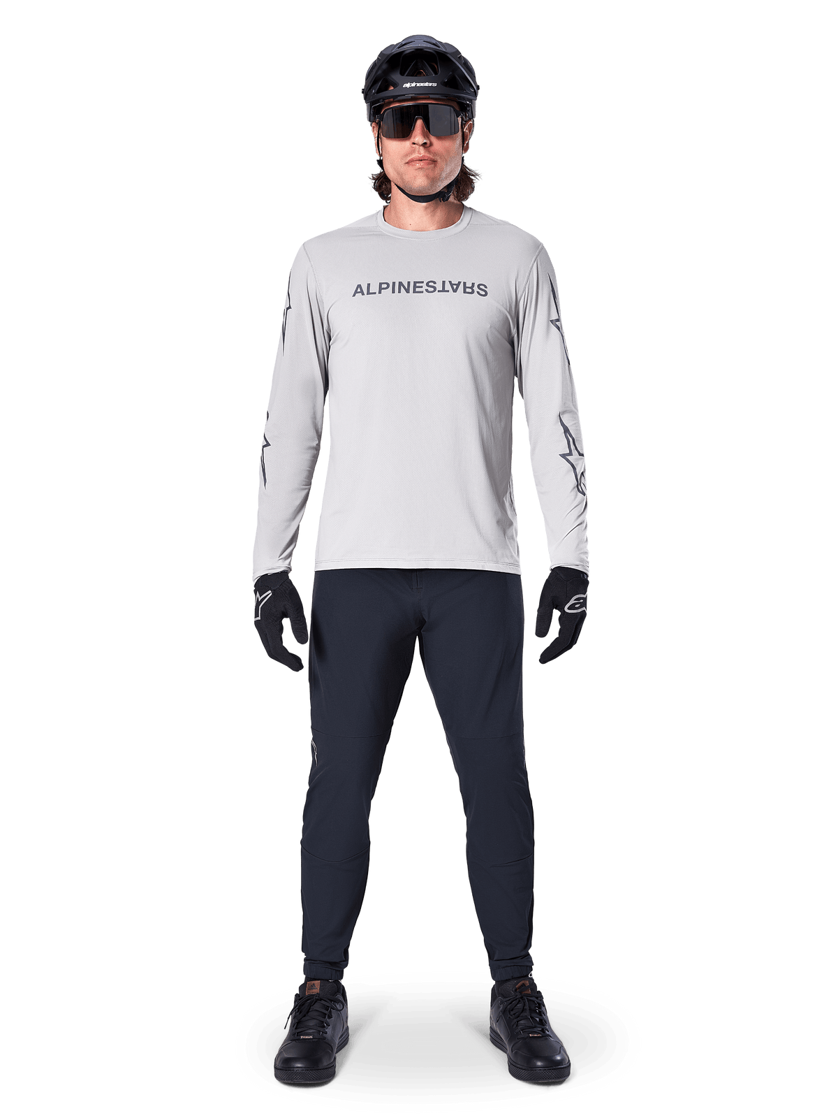 Alpinestars A-Dura Switch langærmet trøje i lysegrå, med stiliseret wordmark-logo på brystet, båret med sorte bukser, hjelm og handsker, performance mountainbike-beklædning til off-road cykling