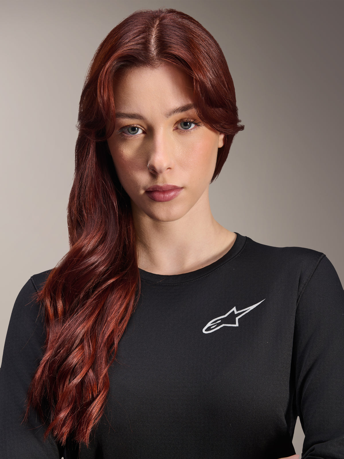 Alpinestars Stella A-Dura Thermal Jersey, langærmet MTB-trøje til damer, sort med hvidt A-star logo på brystet, nærbillede af kvinde med langt rødt hår, cykeltøj til køligt vejr