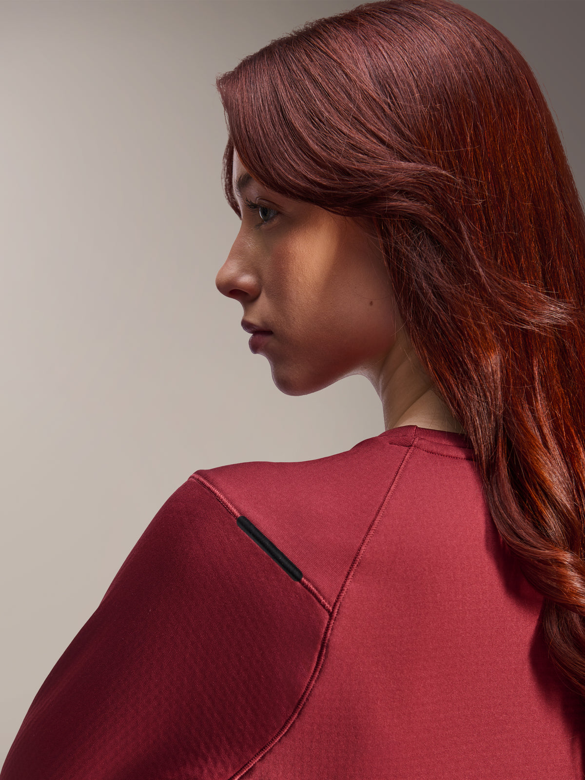 Kvinde iført Alpinestars Stella A-Dura Thermal Jersey, vinrød langærmet MTB-trøje, nærbillede i sideprofil, fokus på skuldersømsdetaljer og materialetekstur, lifestyle cykeludstyr