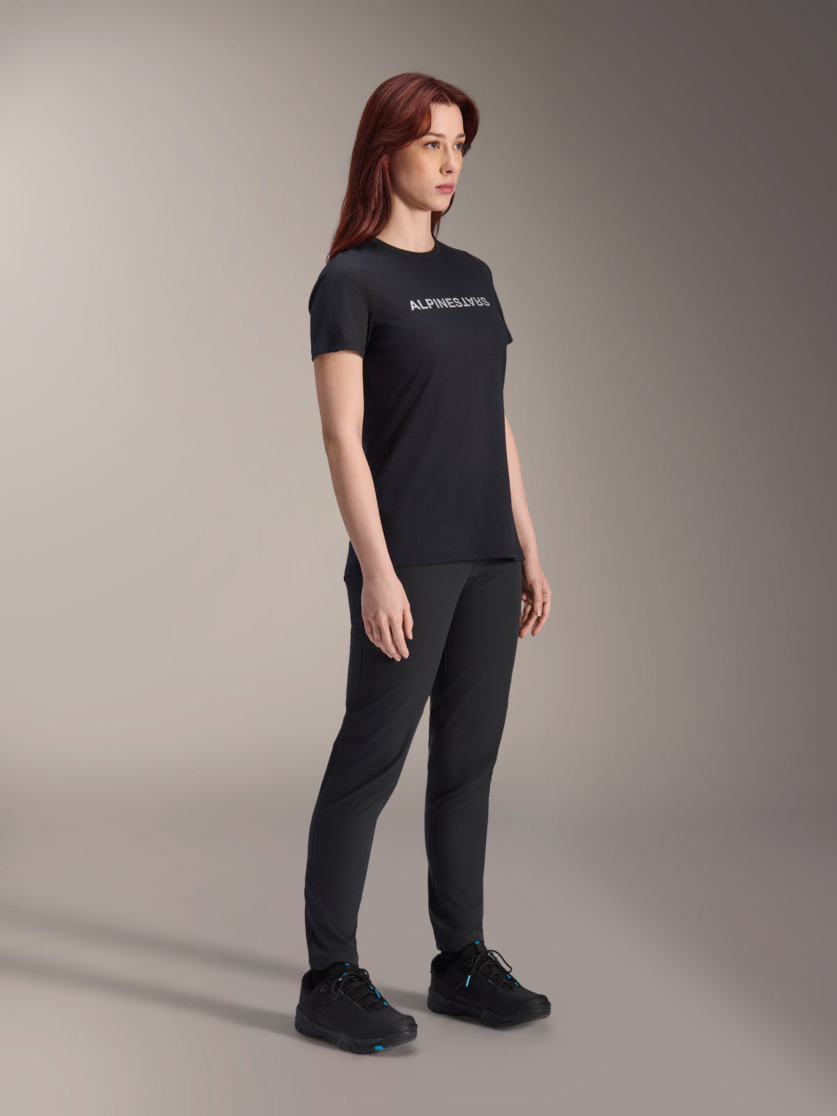 Alpinestars Stella A-Dura Dri Switch Jersey, Short Sleeve Cycling Jersey, Black with white Alpinestars logo, worn by female model with matching black pants and shoes, versatile gear for mountain biking.
