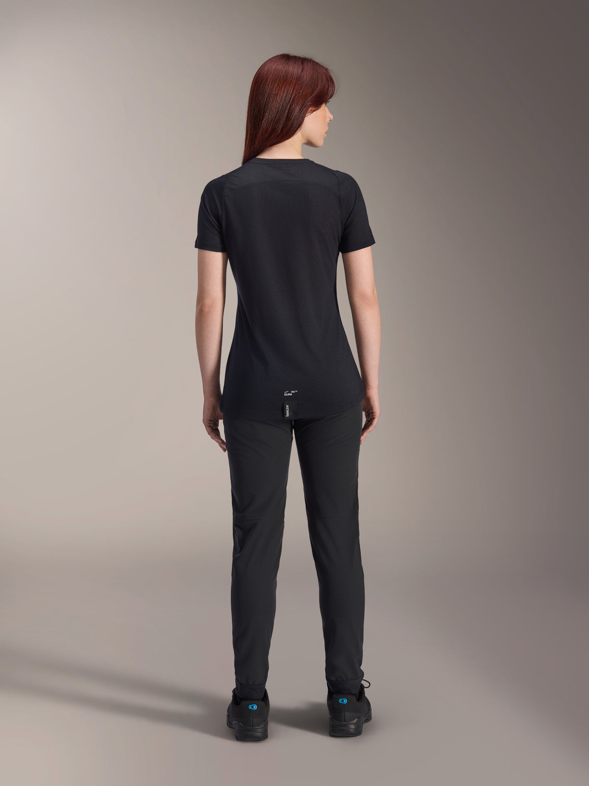 Alpinestars Women Stella A-Dura Dri Switch Short Sleeve Jersey, Black, rear view on a model, featuring a longer drop tail and technical mesh panels, paired with black pants, performance MTB cycling gear