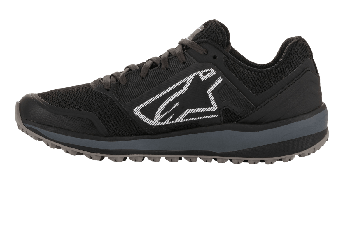 Alpinestars Meta Trail Shoes, performance running shoe, Black and Dark Gray, side profile featuring large white Astars logo, dark gray midsole, lugged oil-resistant rubber sole, designed for paddock comfort and motorsport crew use.