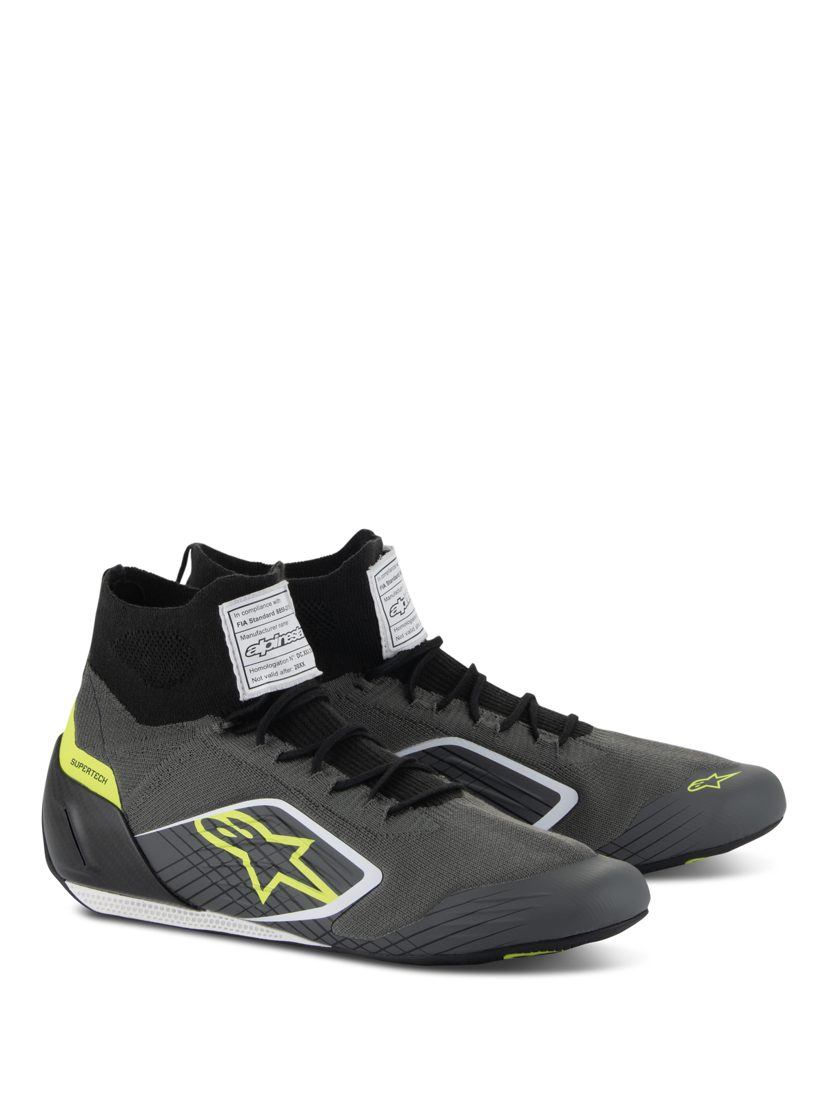 Alpinestars Supertech-sko, køresko til bilsport, kølig grå og sort med fluo-gule detaljer, med strikket aramid-overdel, kulfiberhælskål og hvide FIA-certificeringslabels på pløsen, professionelt motorsportsdesign