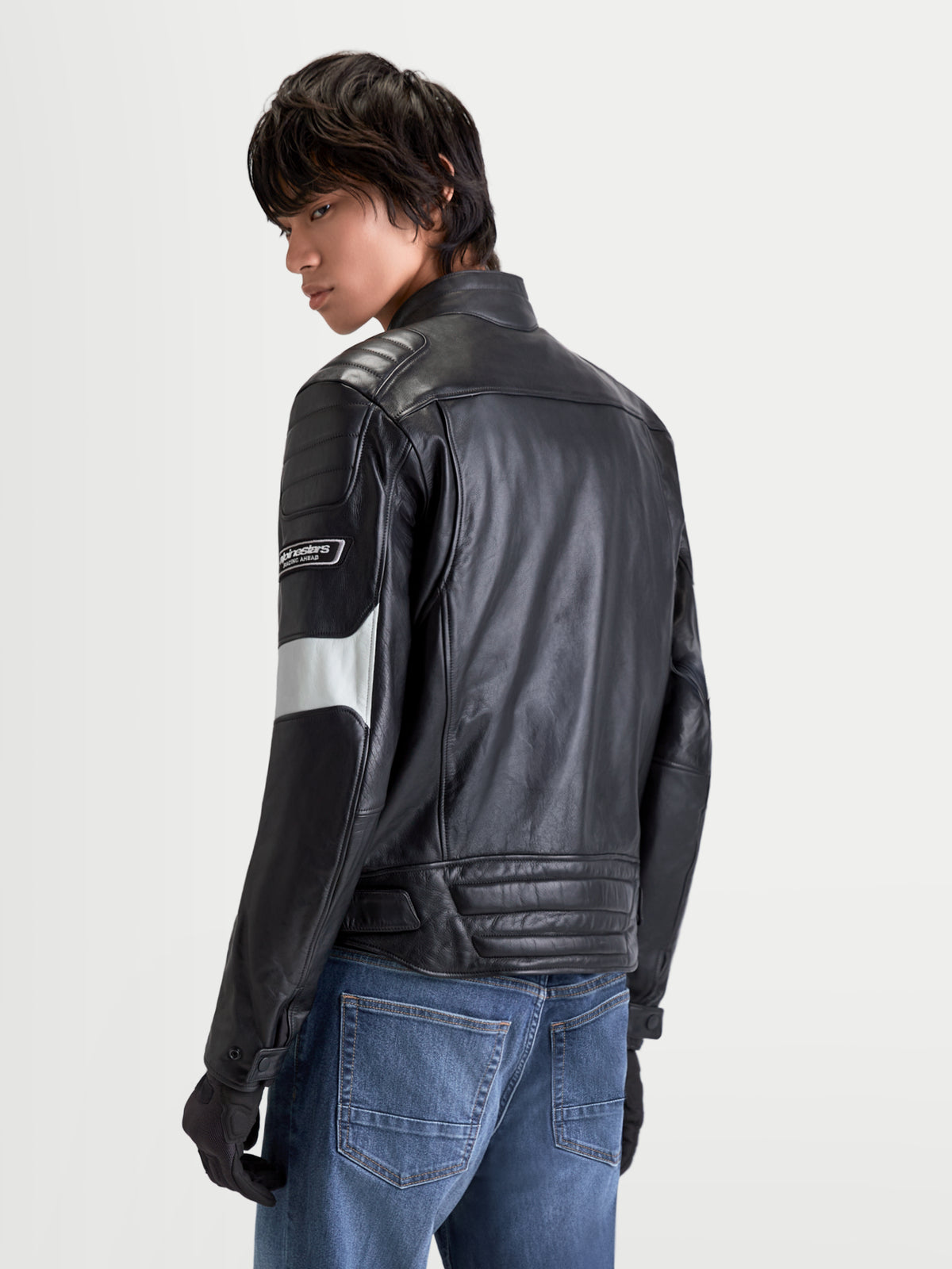 Alpinestars Revern Læderjakke, herre-urban-motorcykeljakke i sort og metalgrå, set bagfra på en model iført jeans, hvilket viser slidt læderkonstruktion og klassisk design