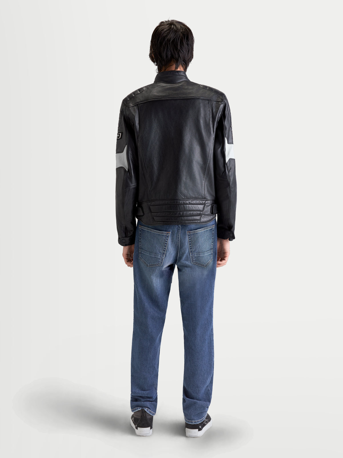Alpinestars Revern Læderjakke, herre-urban-motorcykellæderjakke i sort og metalgrå, set bagfra på en model iført jeans, der fremviser slidt bøffellæder og heritage-stil
