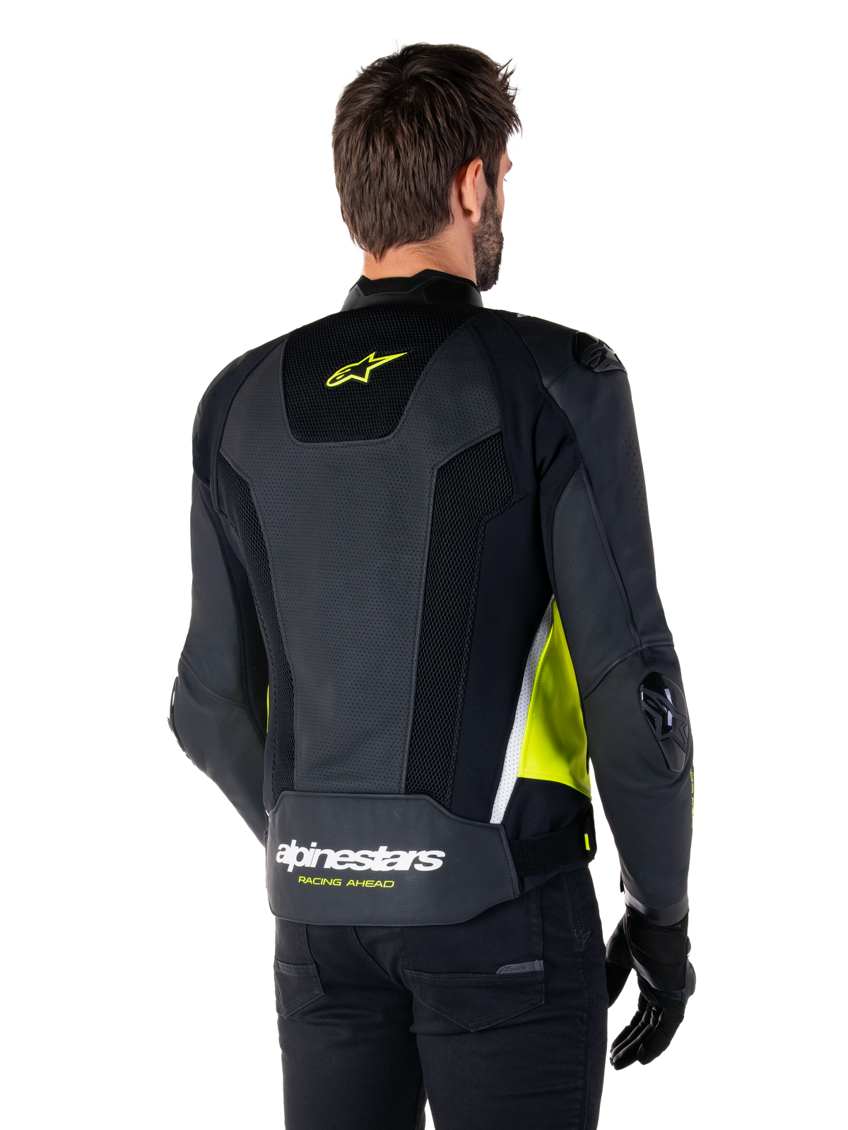 Alpinestars Missile V3 Airflow læderjakke, set bagfra på en mandlig model, sort med fluorescerende gule og hvide detaljer, omfattende perforeret læder og mesh-paneler på ryggen, gult stjerne-logo og hvid 'RACING AHEAD'-tekst, kombineret med sorte handsker og bukser