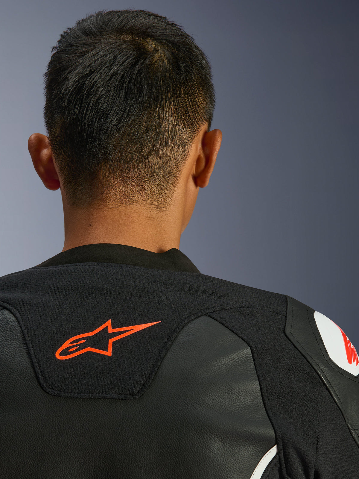 Alpinestars GP Force V2 læderjakke, sort og hvid, nærbillede bagfra af nakke og skuldre, rødt Alpinestars-logo, premium læder med tekstil-strækpaneler, sportsligt performance-design