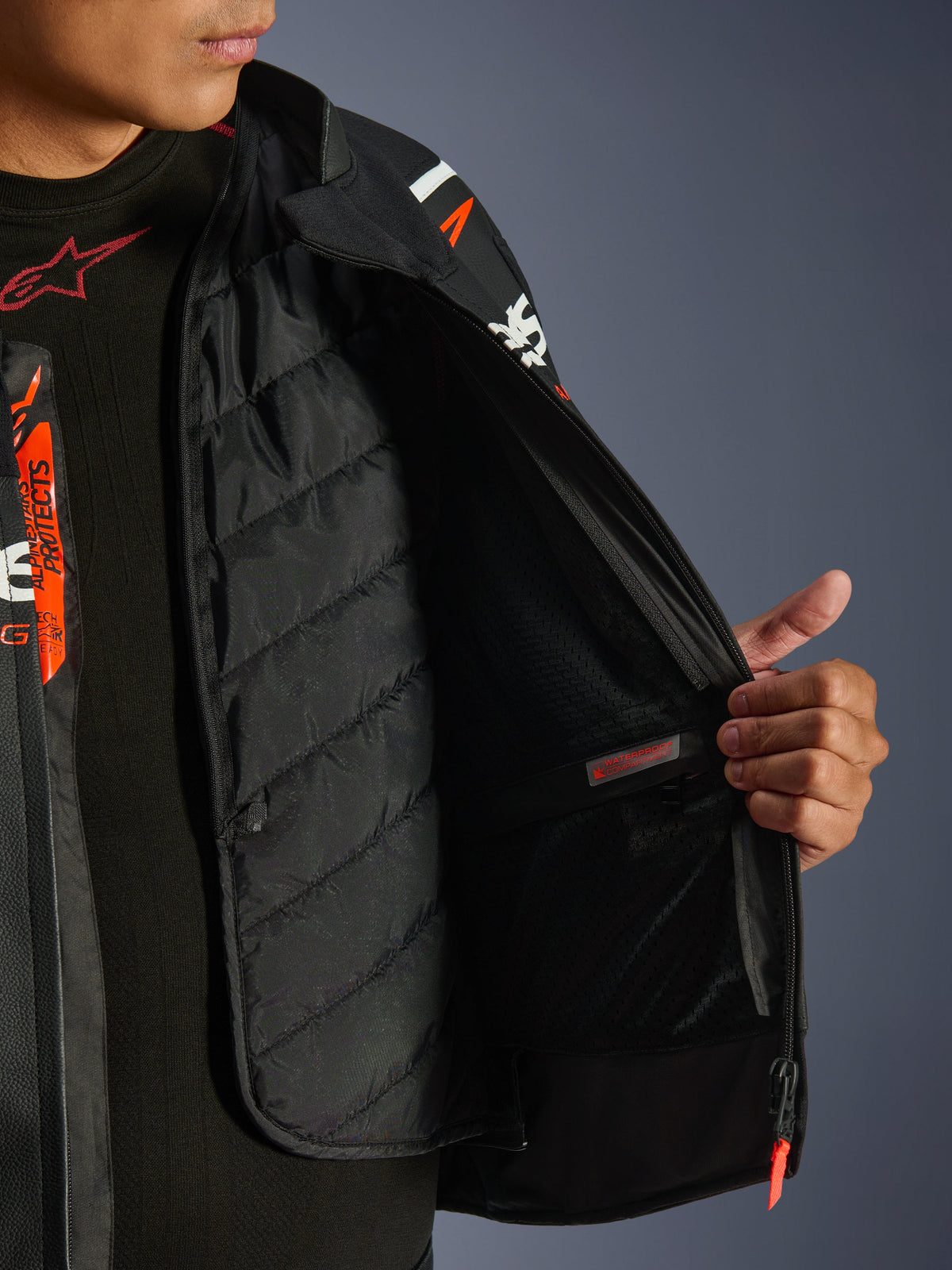 Alpinestars GP Force V2 læderjakke, sort og hvid, detaljeret visning af indersiden, der viser det aftagelige vatterede termofor og den vandtætte inderlomme, båret over et sort baselayer, højtydende motorcykeludstyr