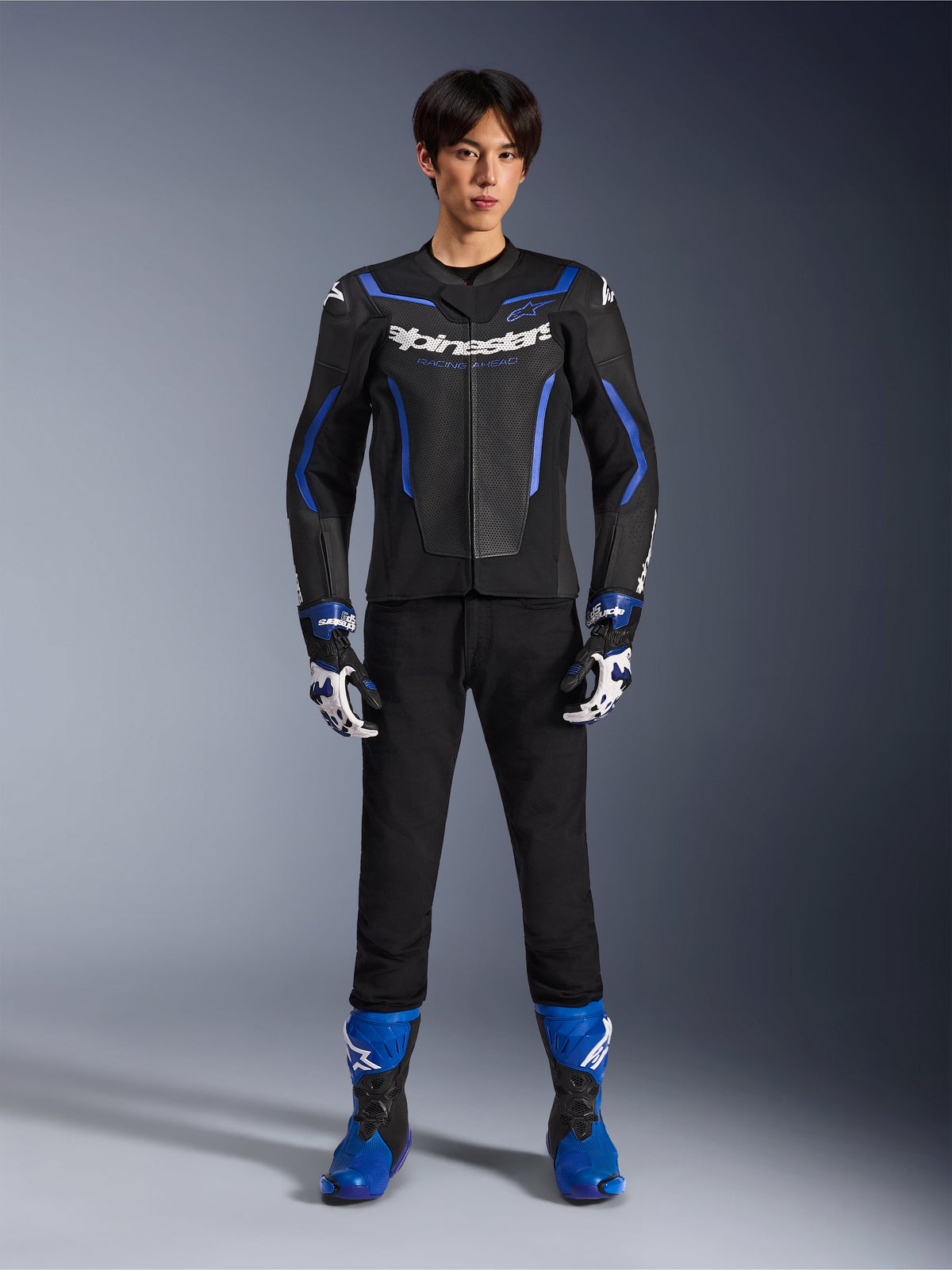Alpinestars GP Force V2 Airflow Leather Jacket in Black Metallic Blue, worn with matching racing gloves, black pants, and blue boots, professional sport motorcycle riding gear, full-body studio shot