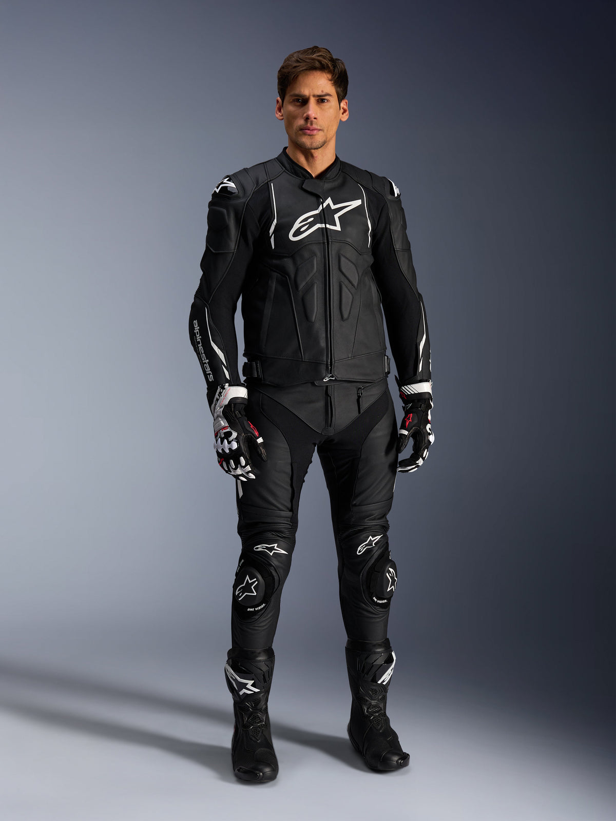 Alpinestars Missile V3 Leather Pants, Black, worn by a male rider as part of a complete leather motorcycle racing outfit, featuring white Alpinestars branding, protective knee sliders, racing boots, and gloves.
