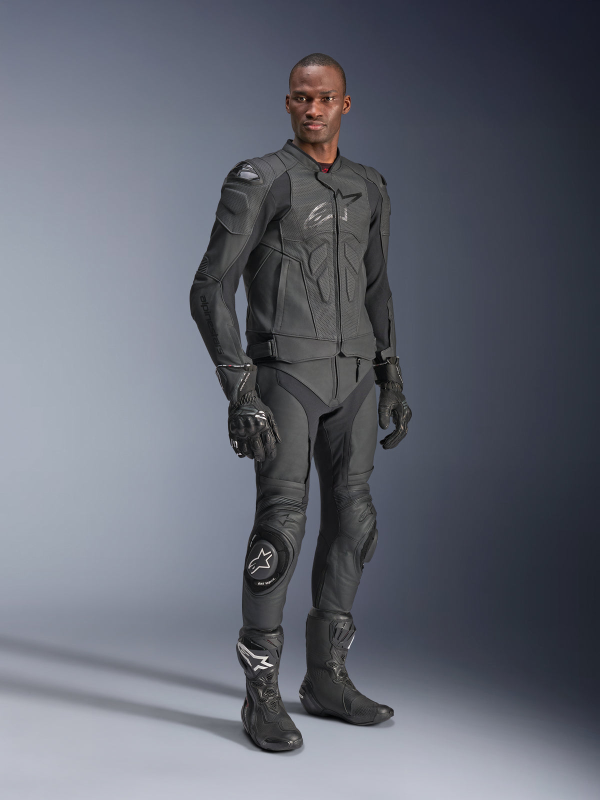 Alpinestars Dusk Airflow læderjakke, sort, båret af en kører i komplet teknisk udstyr inklusive matchende læderbukser, handsker og støvler, med perforerede læderpaneler til ventilation og integreret beskyttelse til sportsmotorcykelkørsel