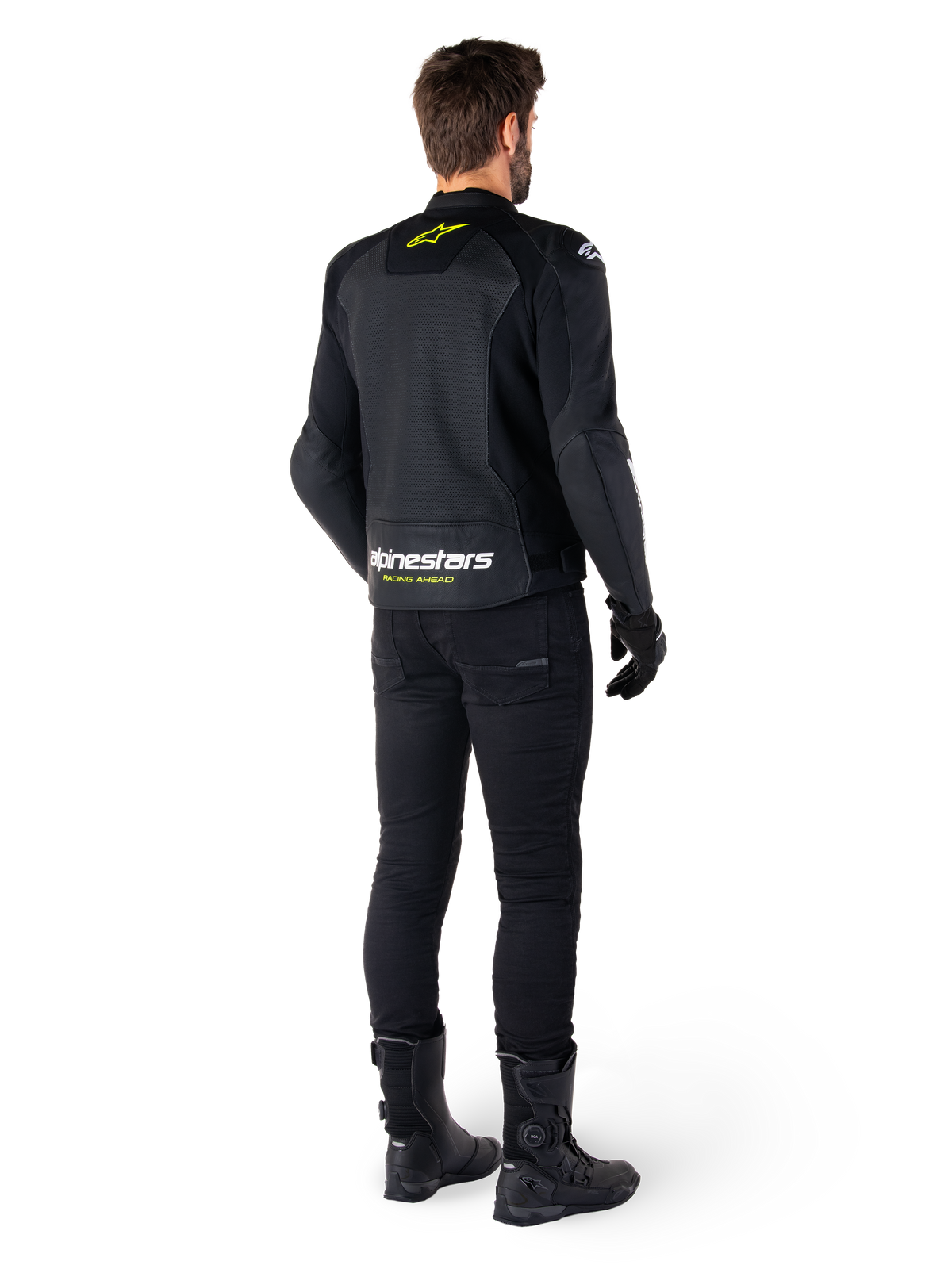 Alpinestars Faster V3 Airflow læderjakke set bagfra, sort med hvide og gul fluo-detaljer, kombineret med sorte bukser og støvler, med perforeret læder for ventilation og markant 'RACING AHEAD' branding på den nederste del af ryggen.