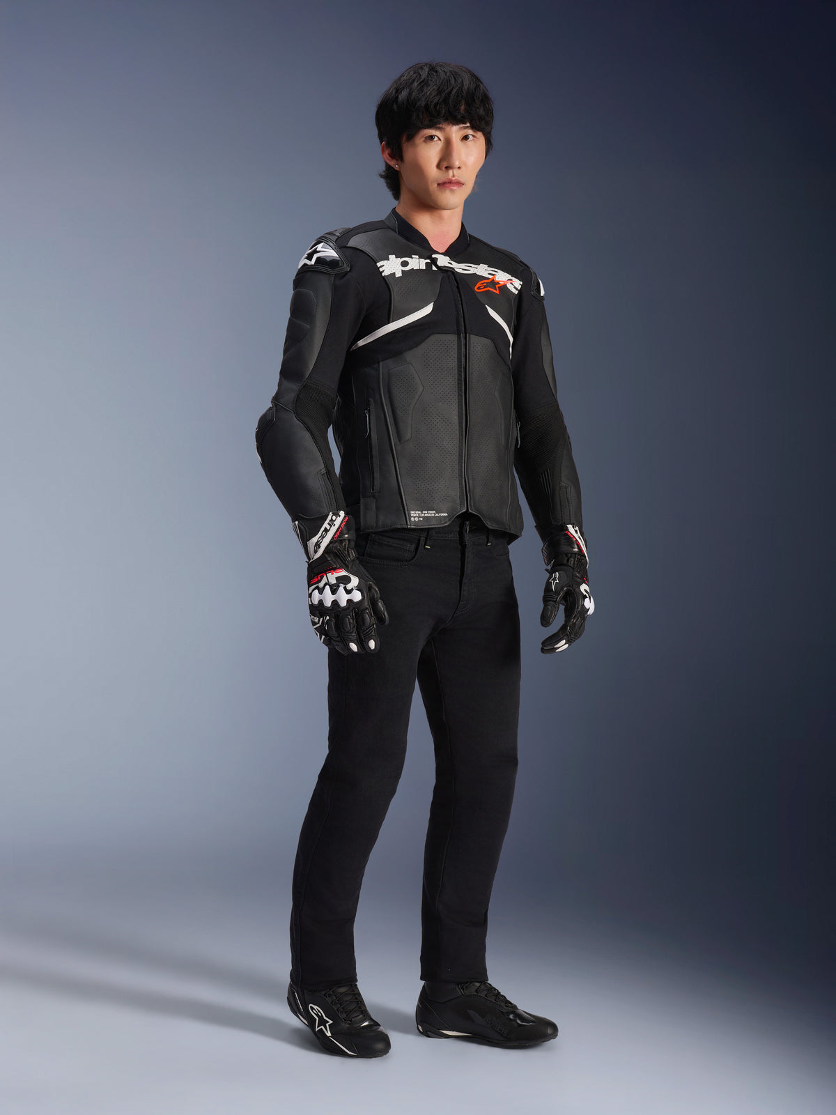 Alpinestars Atem V5 Leather Jacket, Motorcycle Racing Jacket, Black and White, worn with black pants and matching gloves, featuring white Alpinestars branding across the chest and protective shoulder armor.