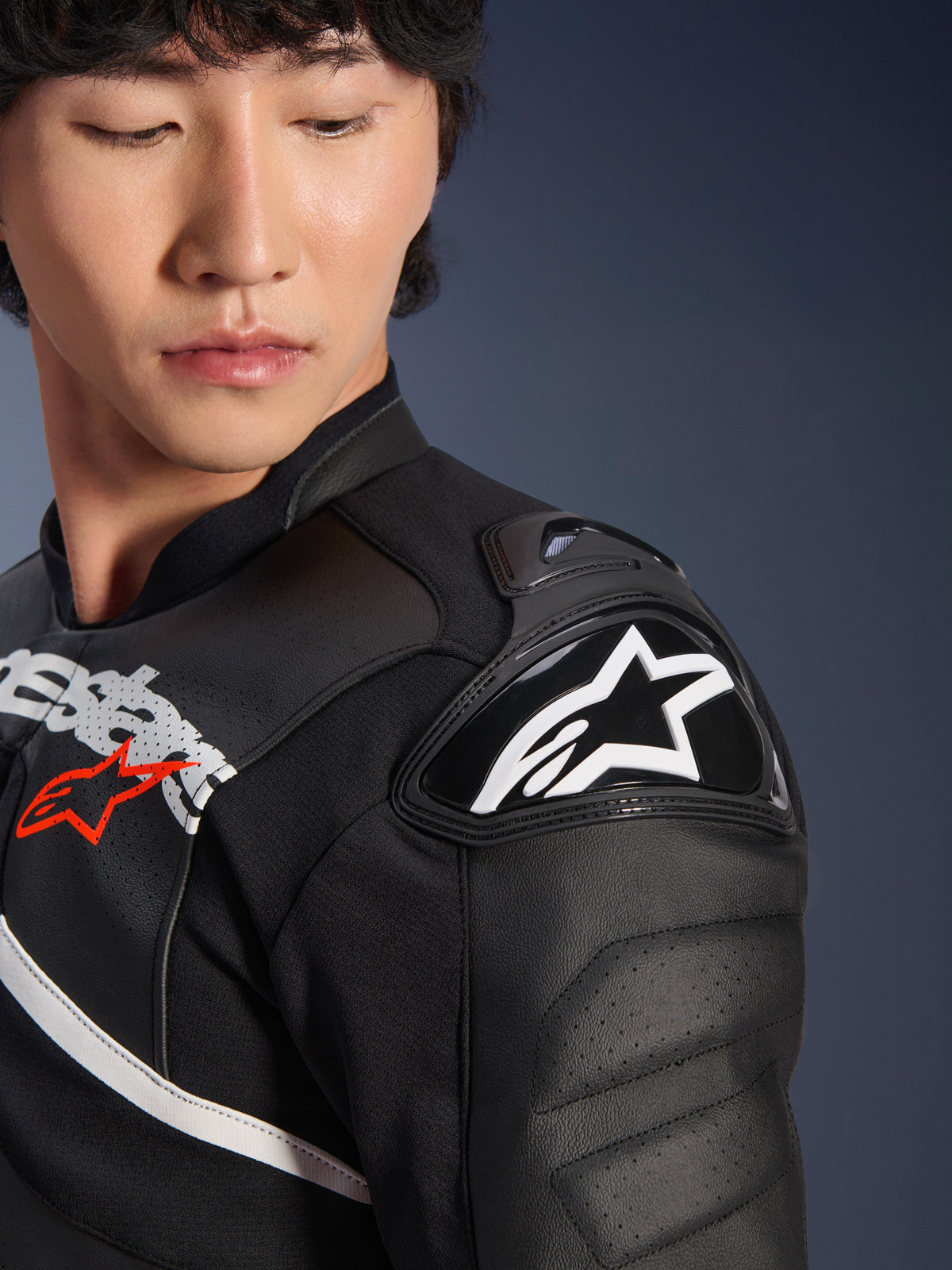 Close-up of the Alpinestars Atem V5 Leather Jacket in Black and White, featuring the DFS RR shoulder protector with white star logo, perforated leather construction, and racing-inspired chest graphics.