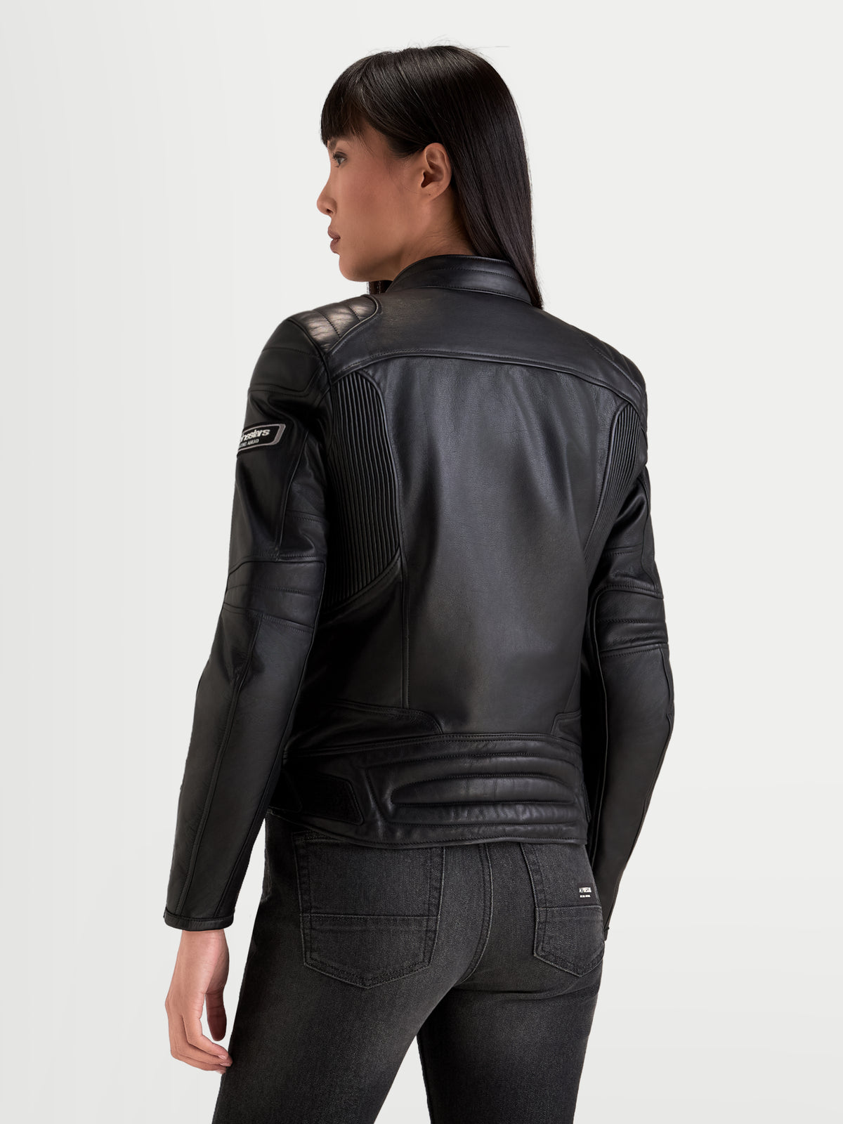 Alpinestars Revea Kvinde læderjakke, sort urban motorcykeljakke set bagfra, der viser premium fuldnarvet okselæderkonstruktion og skulderpolstring båret af kvindelig model