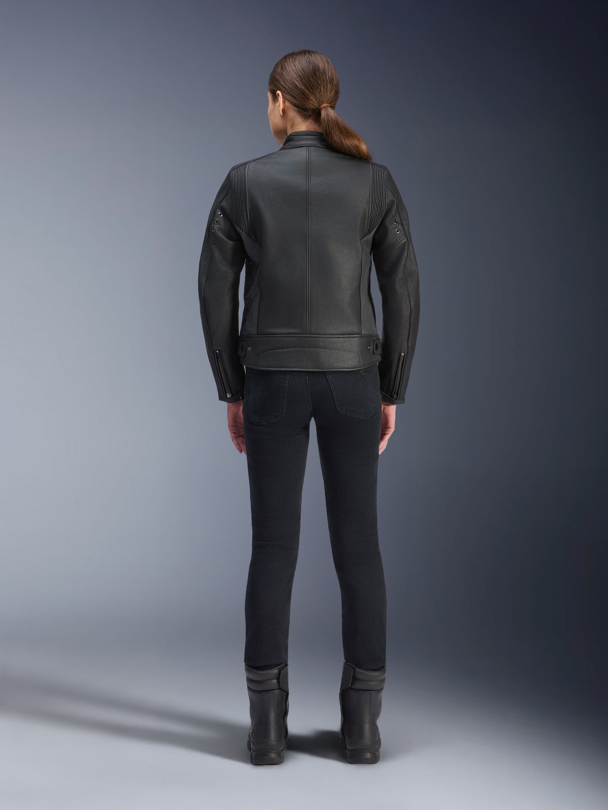 Alpinestars Stella Dyno læderjakke, motorcykeljakke til damer, sort, set bagfra, der fremhæver den skræddersyede konstruktion i bovinelæder, minimalistisk heritage-design, båret med sorte kørebukser og støvler for et urbant motorcykel-look