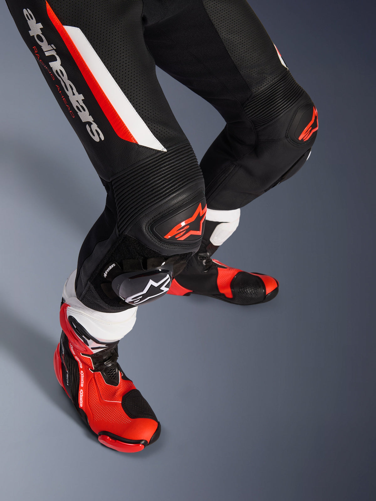 Alpinestars GP Force V2 1-delt læderdragt, sort hvid og rød fluo, nærbillede af underben og knæ med DFS Lite-beskyttere og udskiftelige slidere, kombineret med professionelle racestøvler