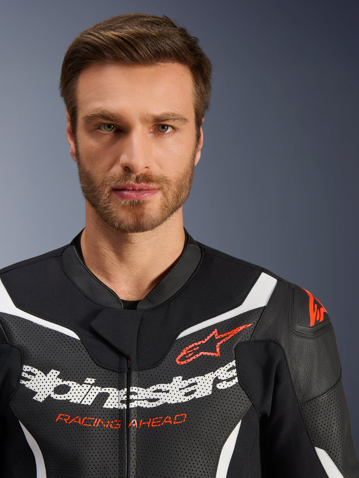 Alpinestars GP Force V2 2-Piece Leather Suit jacket, Black White Red Fluo, close-up portrait featuring perforated leather, white Alpinestars branding and red 'RACING AHEAD' text, performance motorcycle gear