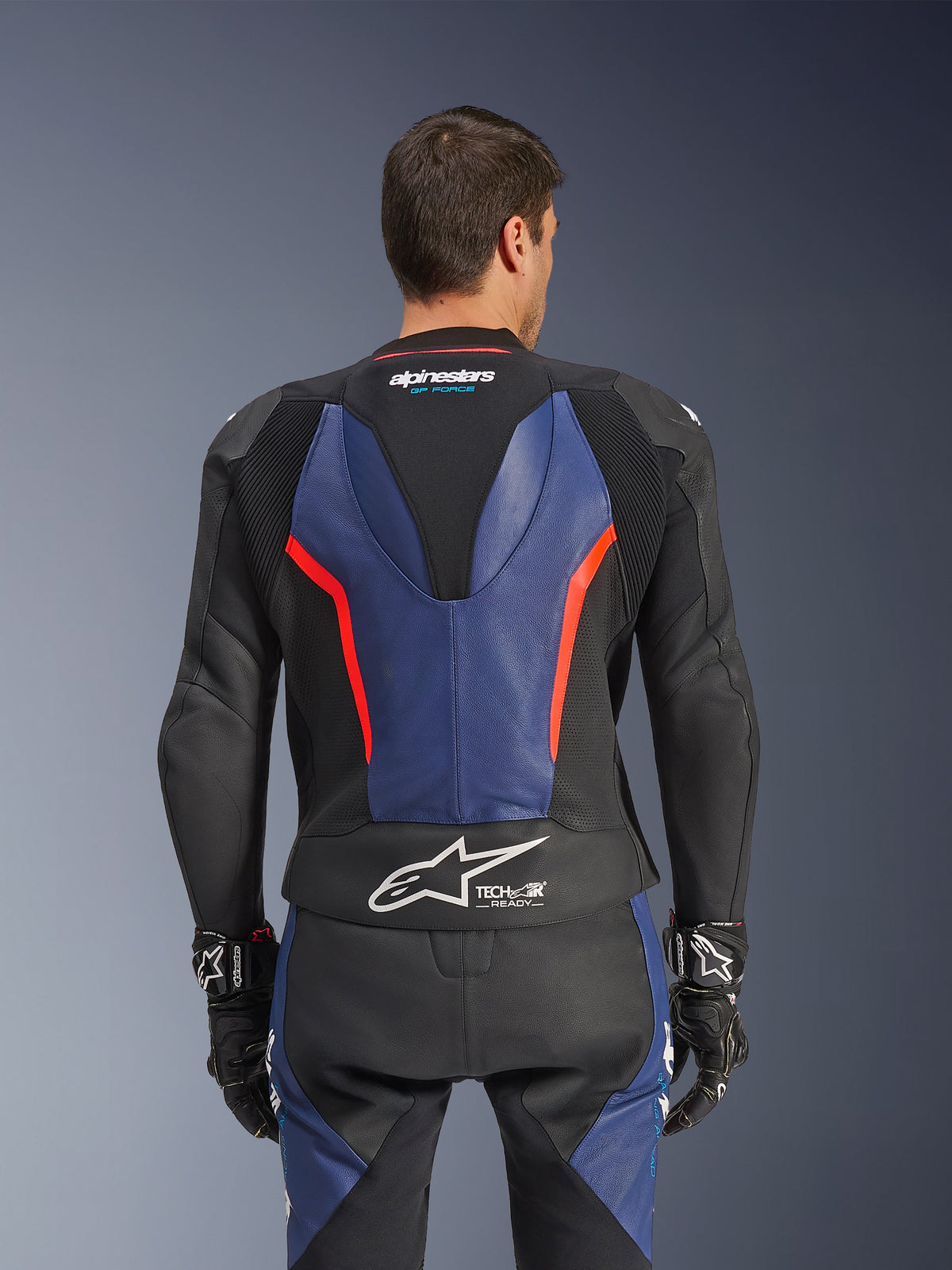 Alpinestars GP Force V2 læderdragt, 2-delt, set bagfra, sort med blå og rød fluo-detaljer, perforeret læderkonstruktion, Tech-Air Ready-branding i taljen, ergonomiske strækpaneler til racerkørsel