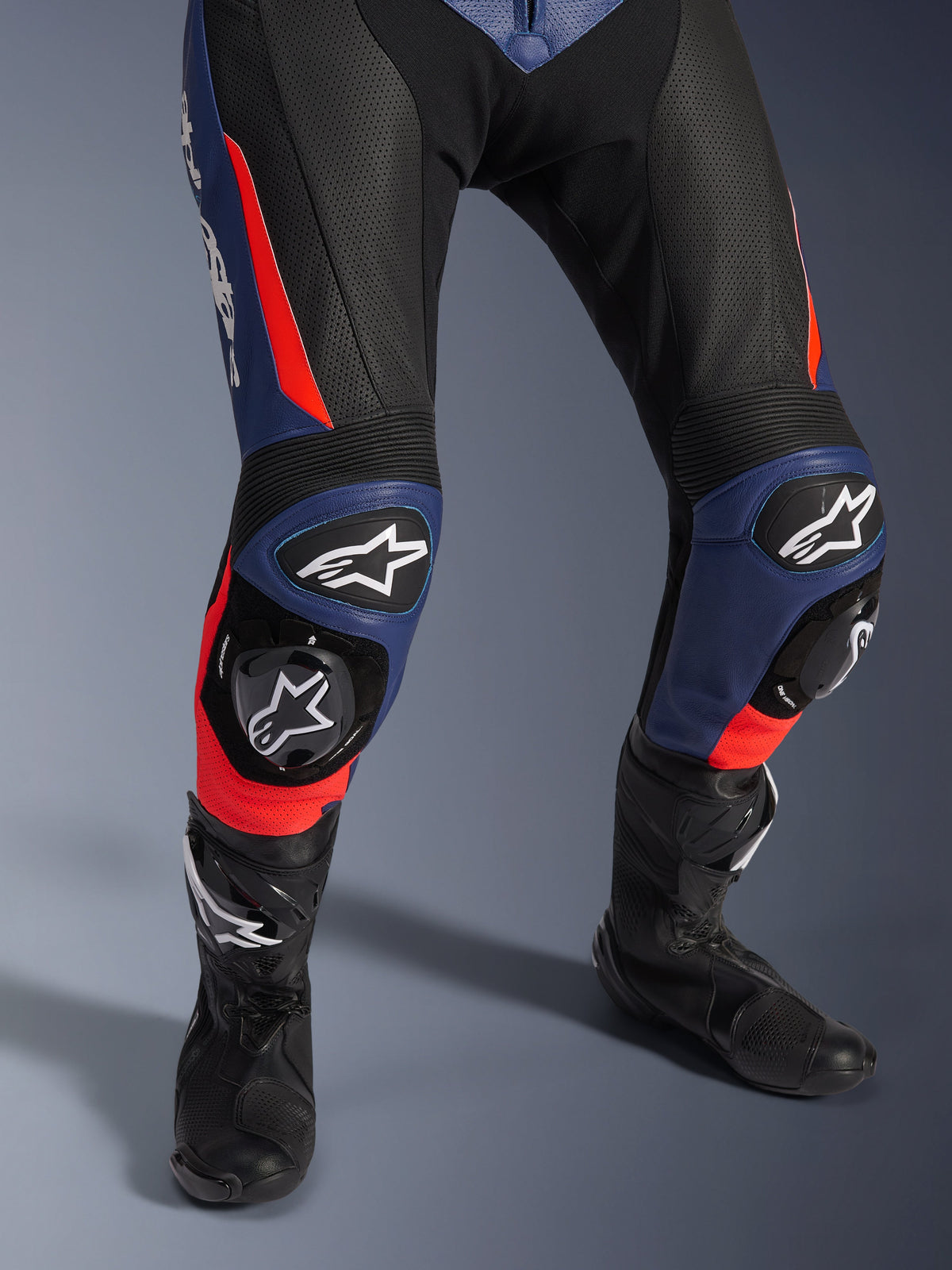 Alpinestars GP Force V2 læderdragt - 2-delt, motorcykelracerdragt, sort, blå og rød fluo, med perforeret læder, harmonika-knæpaneler med beskyttende slidere og Alpinestars logo-branding, kombineret med sorte racerstøvler