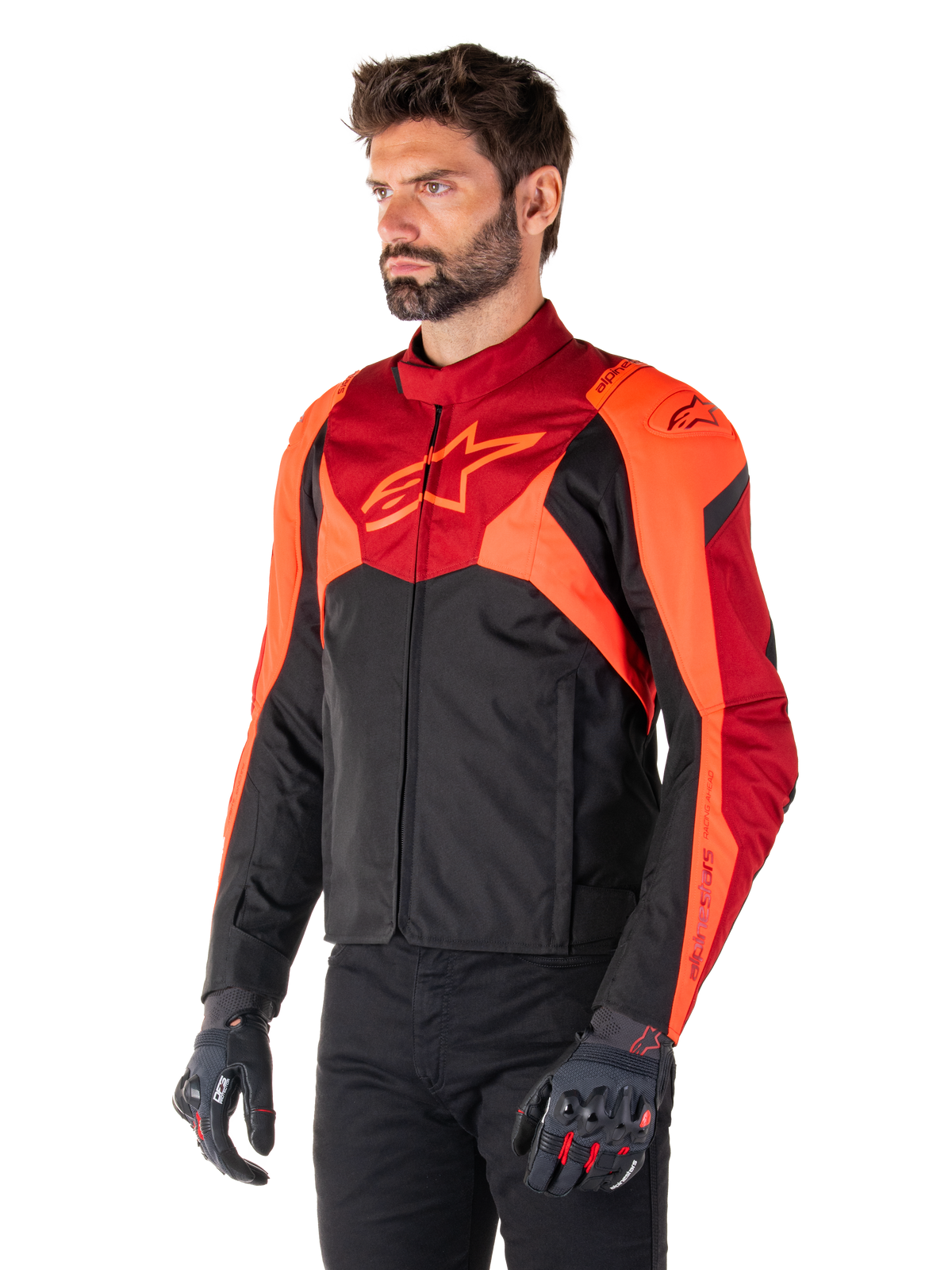 Alpinestars T-Jaws V4 vandtæt jakke, sort, fluorescerende rød og mørkerød, båret af en mandlig model med sorte bukser og motorcykelhandsker, aggressiv sportssilhuet med Alpinestars-logo på brystet, trekvart visning