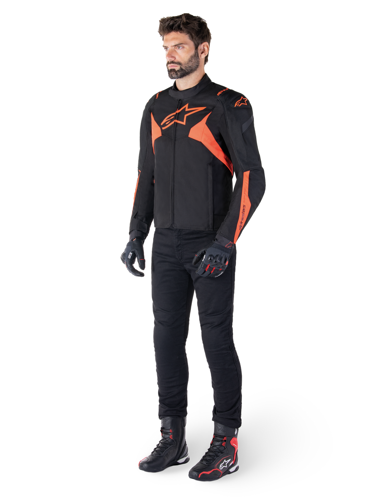 Alpinestars T-Jaws V4 vandtæt jakke, sort og rød fluo, båret af en mandlig model med sorte bukser, handsker og støvler, med klare orange detaljer og Alpinestars-logoet, sporty design til motorcykelkørsel