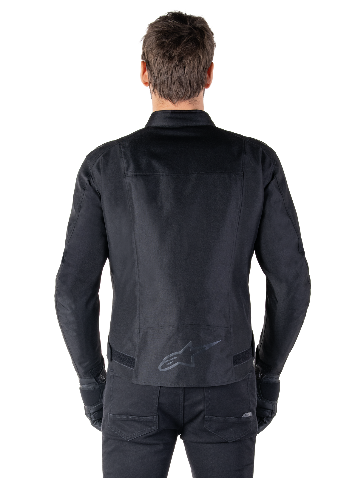Alpinestars T-SPS V2 vandtæt jakke, sort, set bagfra, sportssnit-silhuet, reflekterende Alpinestars-logo på den nederste del af ryggen, forlænget ryg for ekstra dækning under kørsel