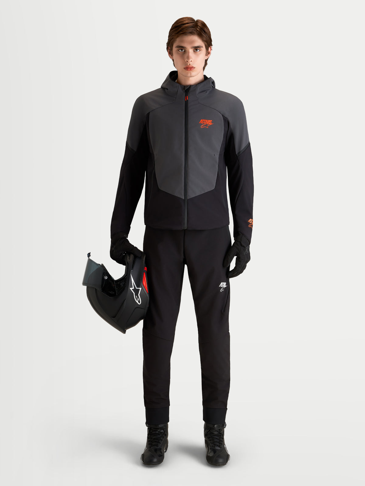 Alpinestars Aeroshell Wp Jakke, vandtæt motorcykeljakke til herrer i sort og mørkegrå, med hætte, model iført jakke og med en motorcykelhjelm