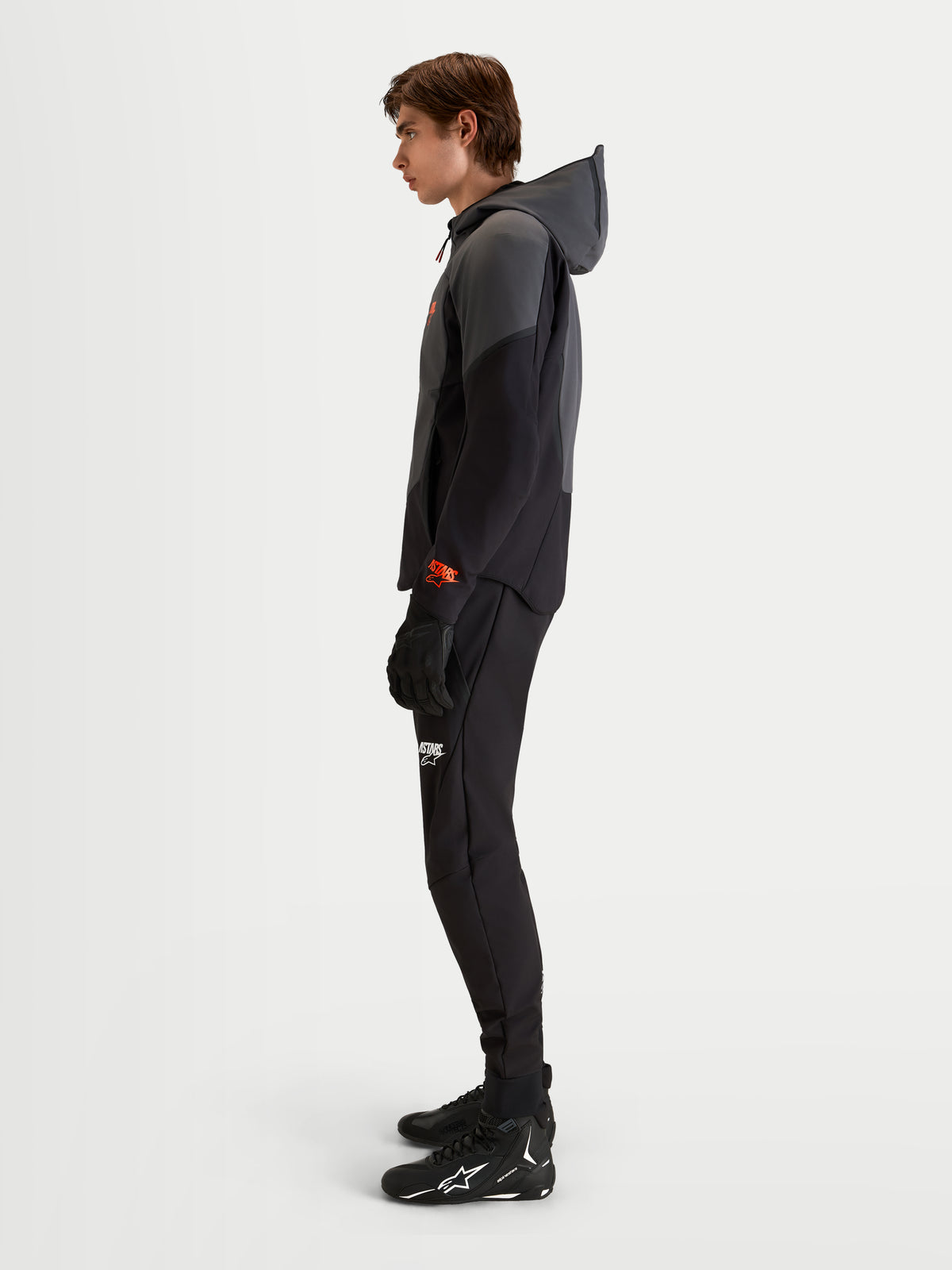 Alpinestars Aeroshell vandtæt motorcykeljakke, herresoftshell-hættejakke i sort og mørkegrå med åben hætte og CE-certificering, båret af en model i profil