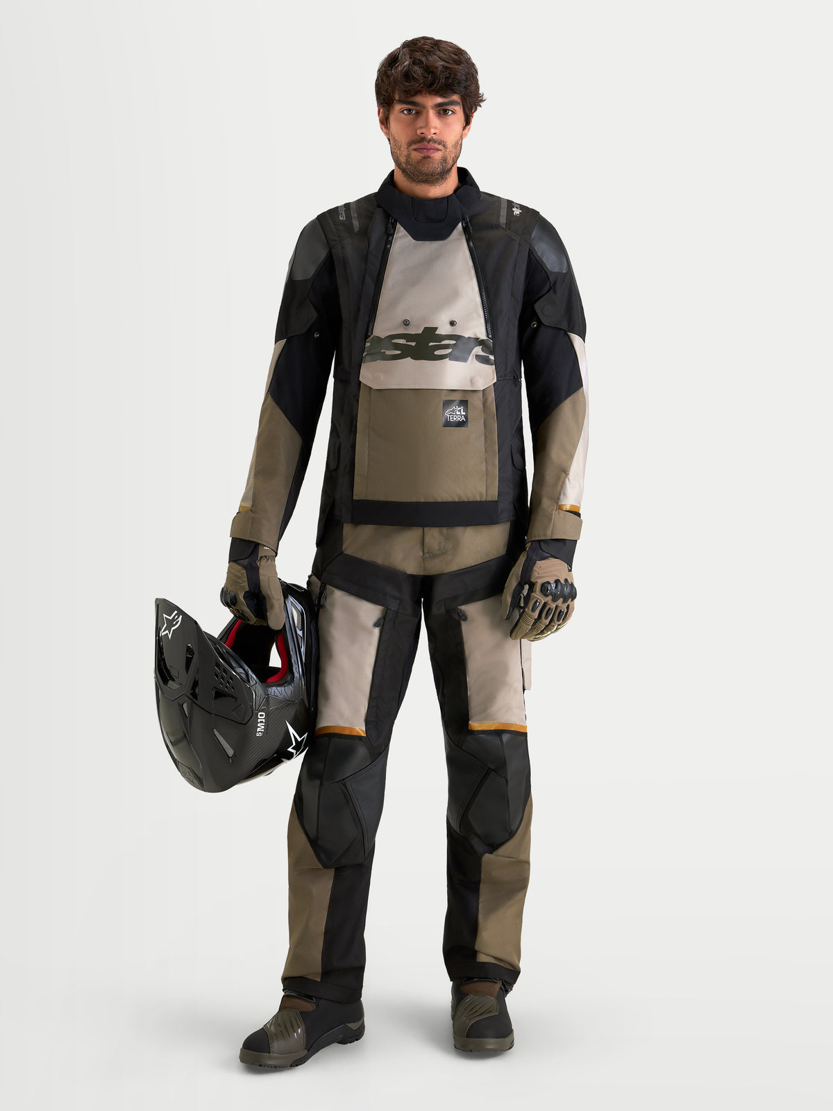 Alpinestars Harok V2 Drystar Gear Set, adventure touring motorcycle jacket and pants in black and khaki, worn by a male model holding an off-road helmet, all-weather waterproof textile riding apparel