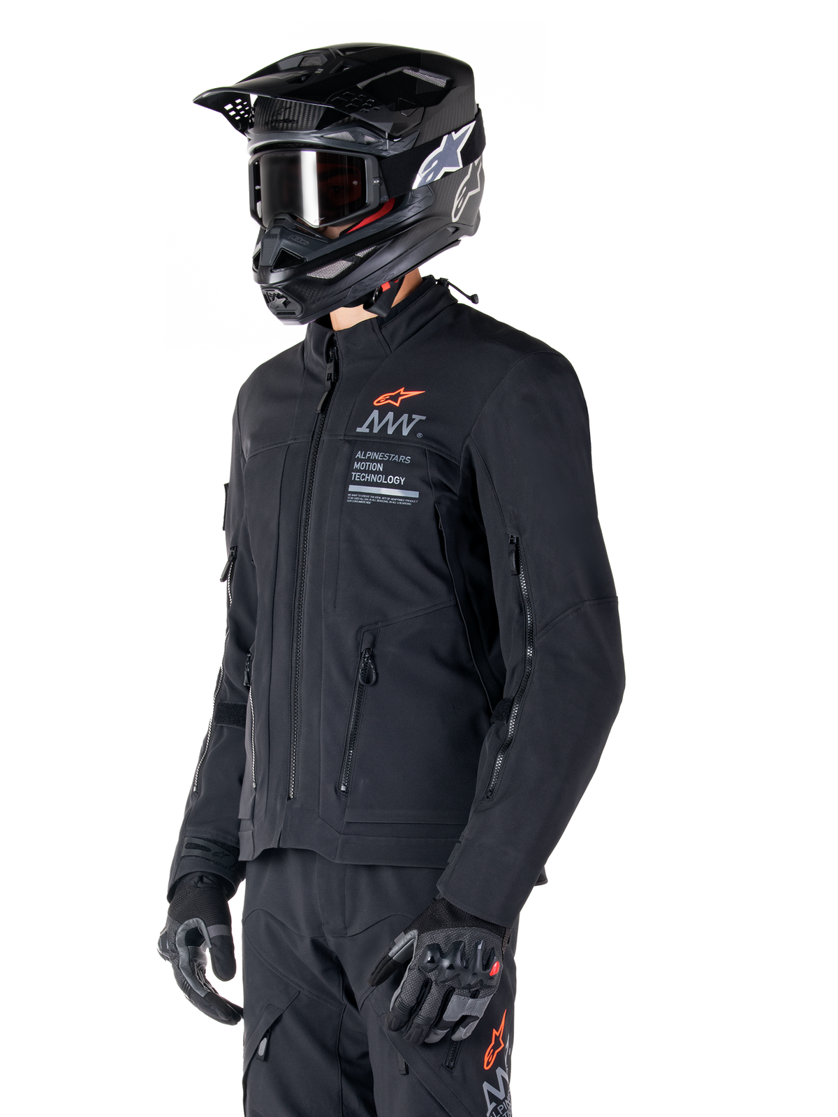 Alpinestars AMT-8 Stretch Drystar® XF jakke, sort, båret af en kører med matchende adventure-bukser og -handsker, sort motocross-hjelm og goggles, ventilationsåbninger med lynlås på bryst og arme, Alpinestars Motion Technology-branding med orange logo, førsteklasses adventure-touring-udstyr
