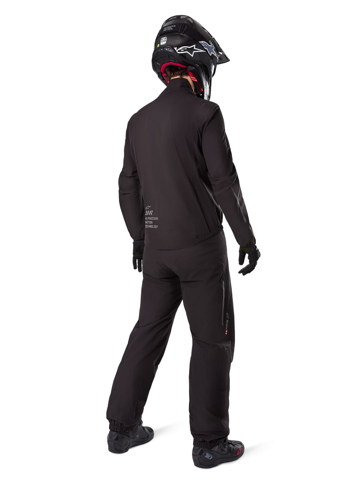 Set bagfra af en kører iført Alpinestars AMT-8 Stretch Drystar® XF jakkeforing, sort teknisk motorcykeludstyr, båret med matchende bukser og sort hjelm, med "AMT Alpinestars Motion Technology" branding på ryggen, strømlinet minimalistisk design til adventure touring