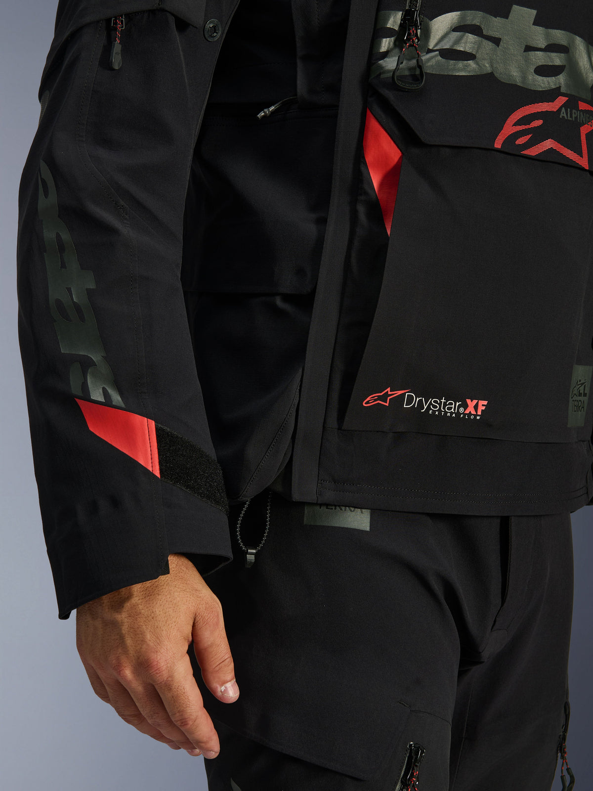 Alpinestars Halo Pro Drystar® XF lamineret jakke, motorcykeljakke, sort med røde detaljer, nærbillede med Drystar® XF-branding, teknisk lamineret skaltekstur og justerbare ærmedetaljer til adventure-kørsel