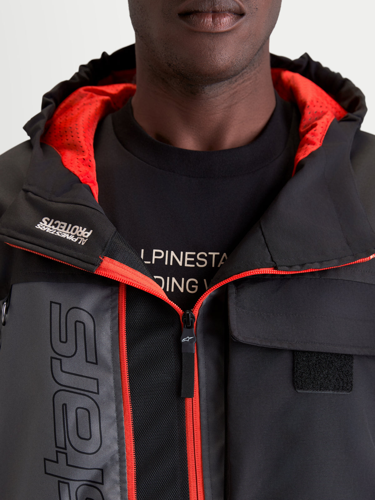 Alpinestars Morfex Parka Waterproof Jacket, men's urban contemporary motorcycle jacket in lunar gray and black, close-up view showing the integrated hood, red inner lining, and front chest pocket details worn by a model.