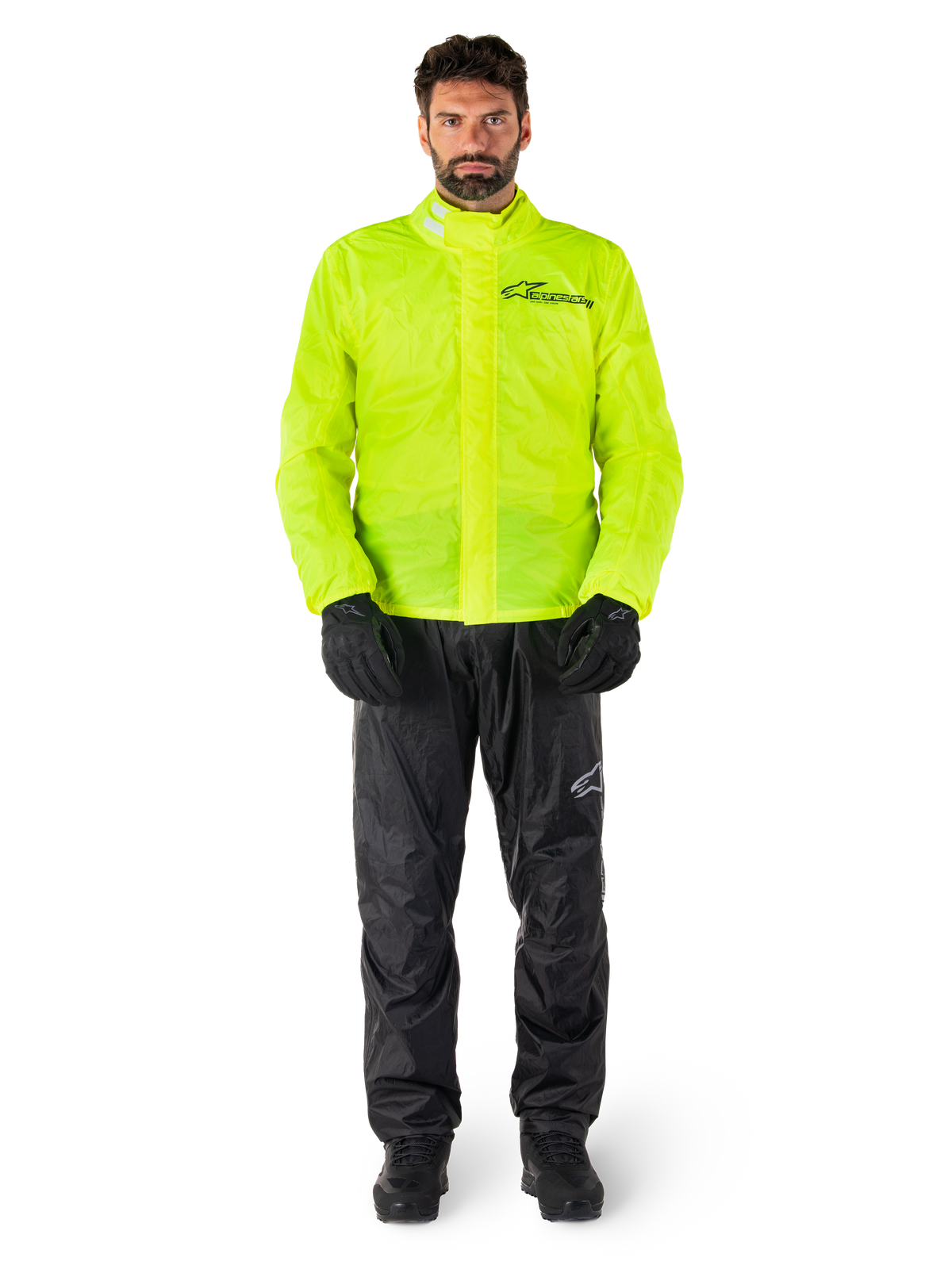 Alpinestars Hurricane Rain V2 jakke og bukser, neongul og sort, vandtæt motorcykelregnsæt båret med sorte handsker og støvler, med Alpinestars-logo på brystet og benet