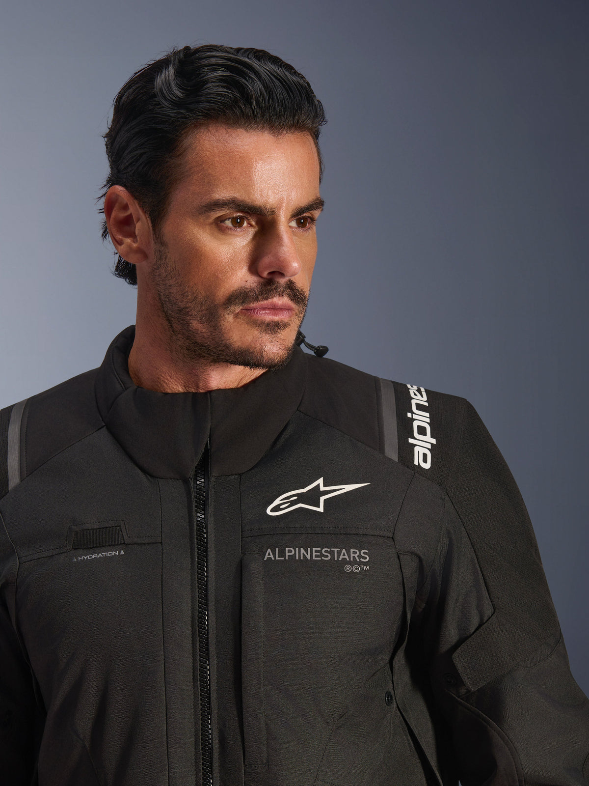 Alpinestars Andes V4 Drystar® jakke, sort, båret af en mandlig model, nærbillede af bryst og skuldre, hvide Alpinestars-logoer, tekstilmateriale med ventilationsdetaljer og væskeløkke, adventure-touring motorcykeludstyr