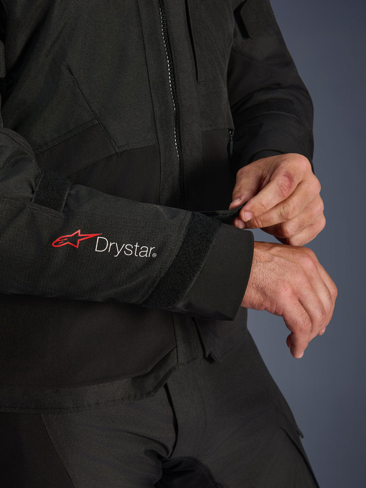 Alpinestars Andes V4 Drystar® jakke, sort tekstil-motorcykeljakke, nærbillede af ærmet med rødt Alpinestars- og hvidt Drystar®-branding, kører der justerer velcroremmen ved håndleddet for en sikker pasform, funktionel detalje til adventure-kørsel