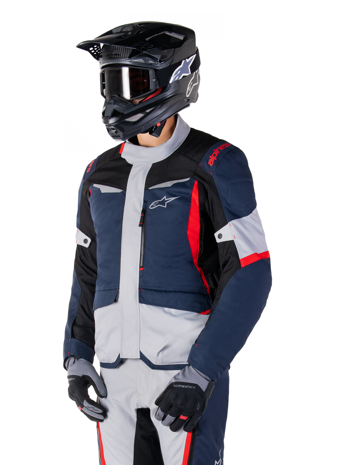Alpinestars ST-1 Waterproof Jacket, adventure touring motorcycle jacket in Dark Blue, Black, and Bright Red, worn with a black helmet and grey gloves, featuring a modern design with functional pockets and Alpinestars branding.