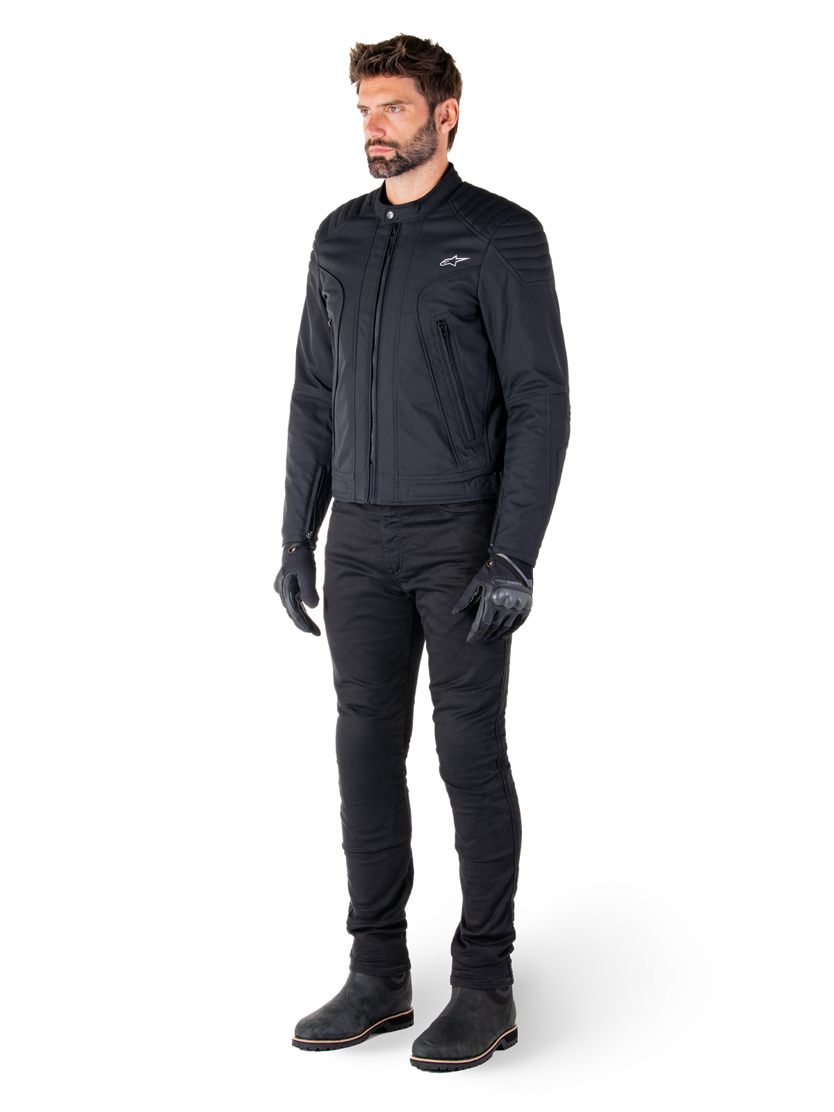 Mandlig kører iført Alpinestars Clayton WR-jakken, sort urban motorcykeljakke, slim-fit design med quiltede skulderdetaljer og mat finish, kombineret med sorte tekniske kørebukser og handsker.
