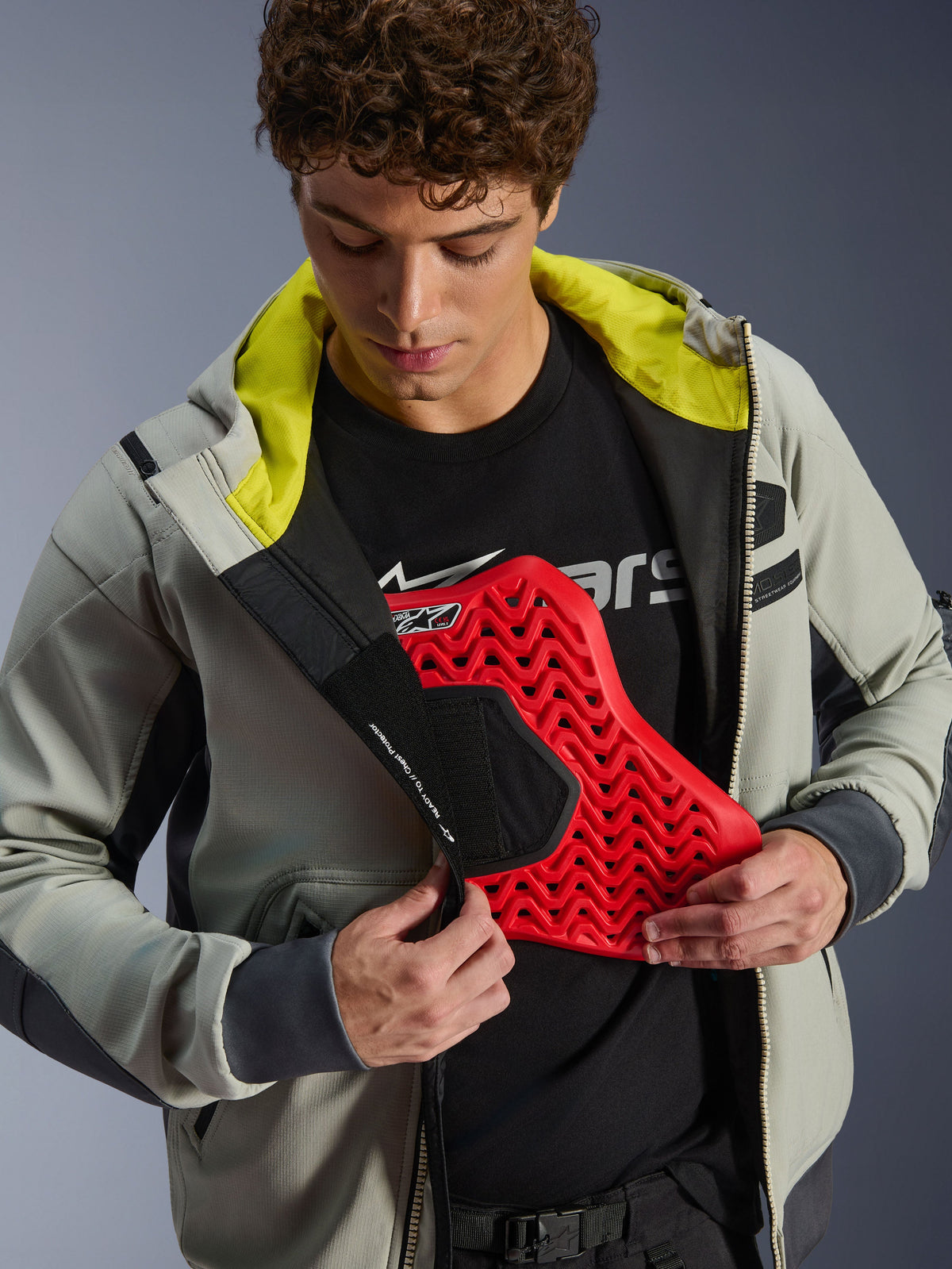 Alpinestars Moblast vandtæt jakke, Iron Gray og Dark Sage, model der demonstrerer integration af brystbeskyttelse med et rødt beskyttelsesindlæg, lyst limegrønt indvendigt for, moderne urbant motorcykeludstyr