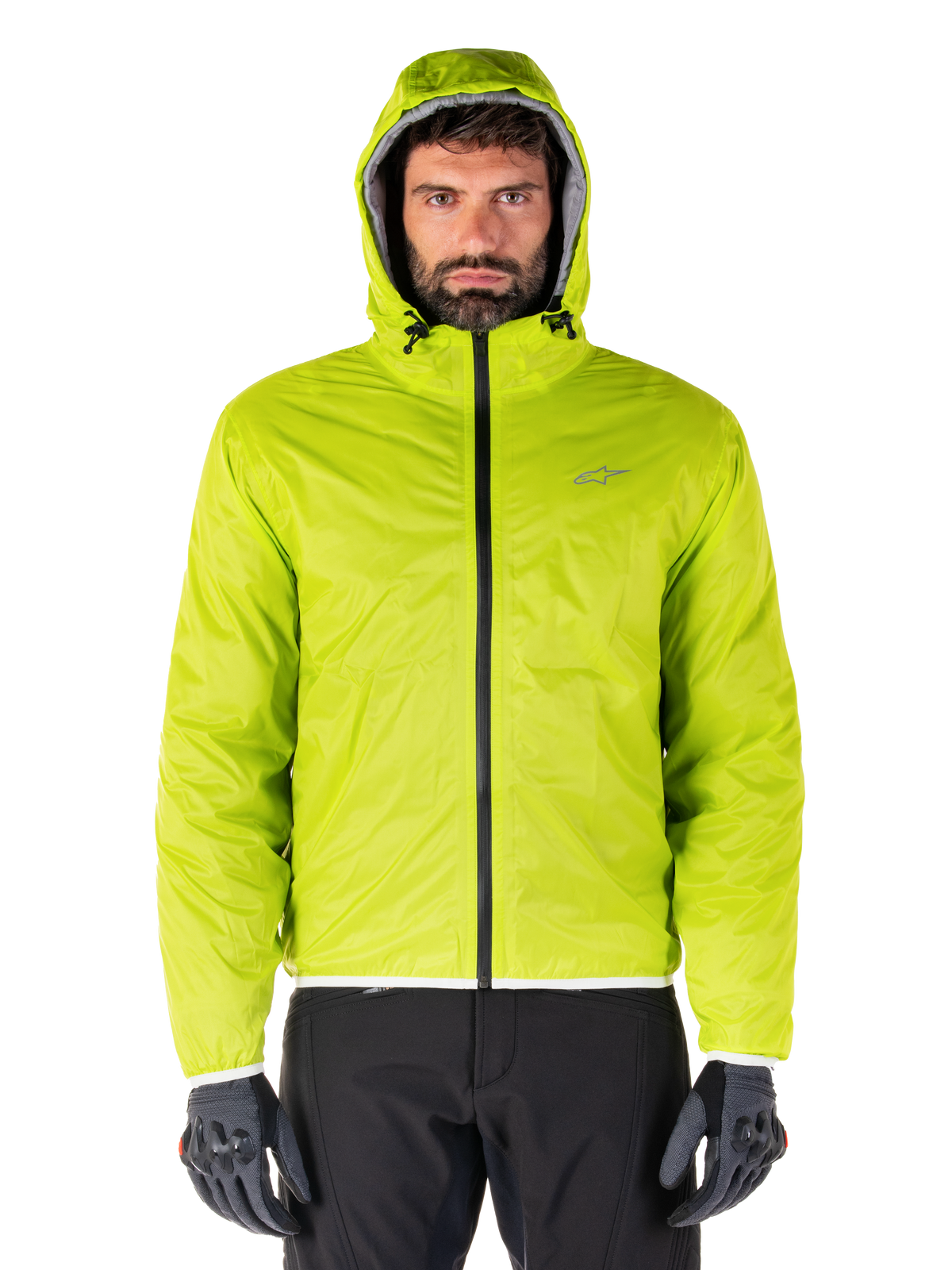 Alpinestars Mohobbs Waterproof Jacket, Lime Punch pakkebart regnslag, klar limegrøn skaljakke med hætte båret med sorte kørebukser og grå motorcykelhandsker, urban moto-streetwear stil