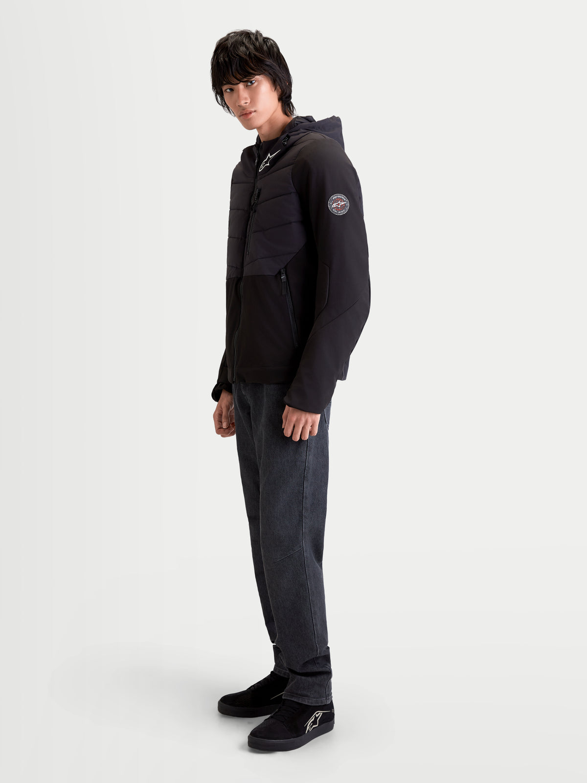 Alpinestars Therma Tech WP jakke, sort urban motorcykeljakke, sideprofil set på en mandlig model der viser svejset dunjakke-konstruktion og integreret hætte