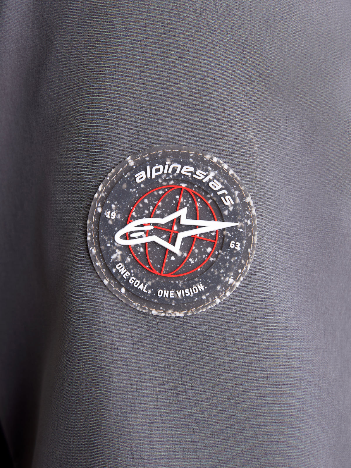 Alpinestars Therma-Tech WP jakke, nærbillede af det cirkulære mærkelogo på ærmet i mørkegrå tekstil, med A-star-emblem og signaturbranding