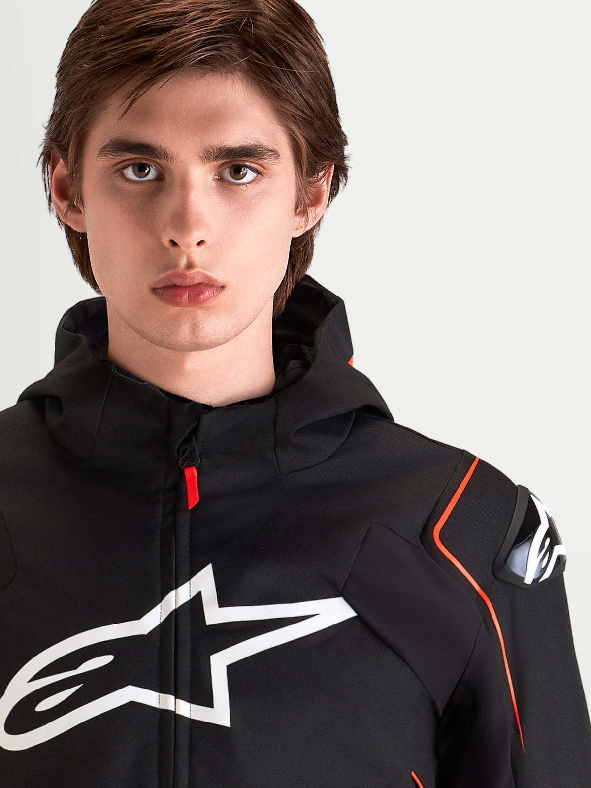Alpinestars Zaca V2 Waterproof Jacket, men's waterproof sport motorcycle jacket, Black and Red Fluo, featuring DFS shoulder armor and large chest logo, close-up portrait of a male rider