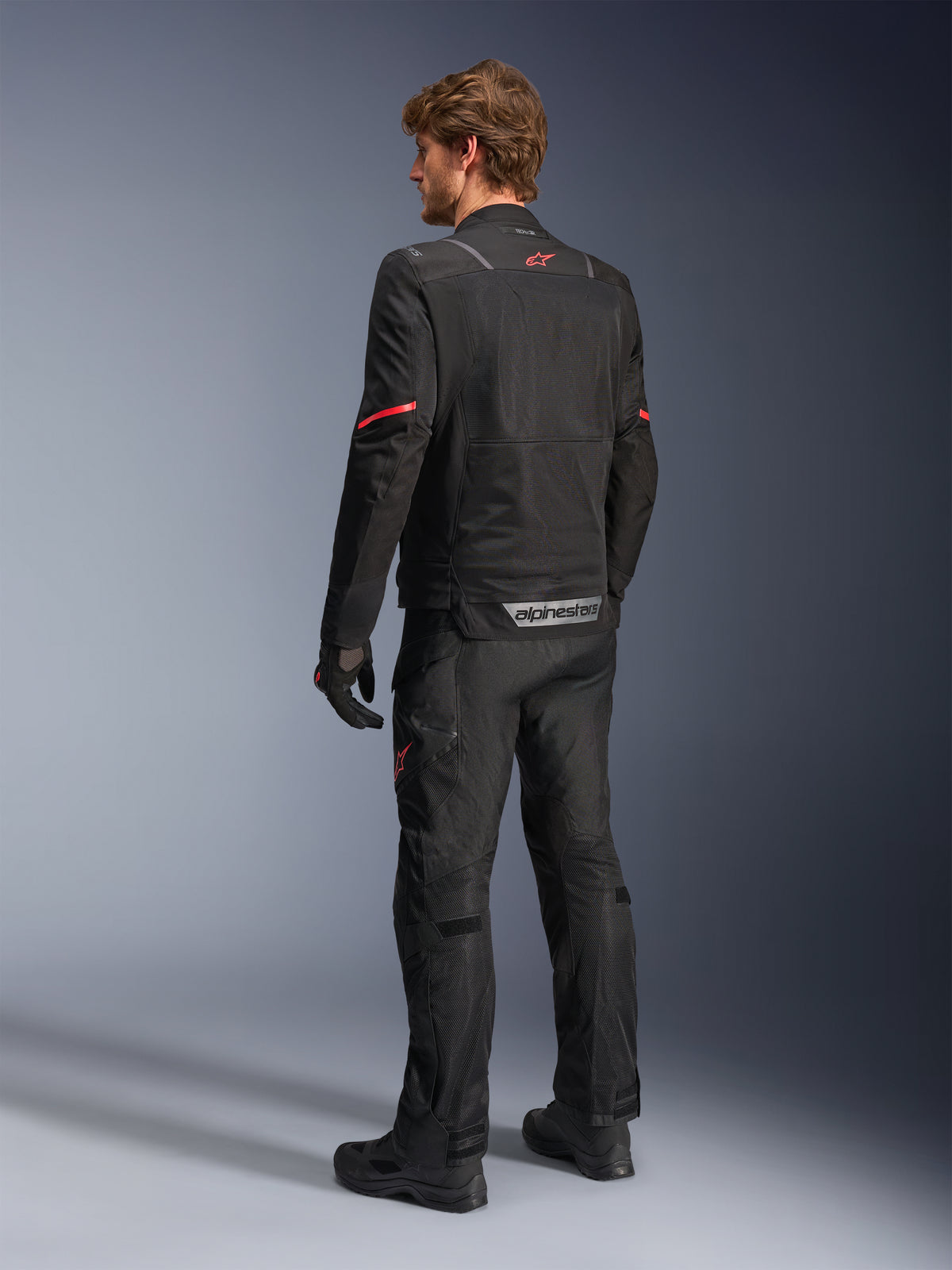 Alpinestars ST-2 Air Jakke, sort adventure touring motorcykeljakke til herrer, mesh-paneler, rødt stjernelogo, set bagfra på model.