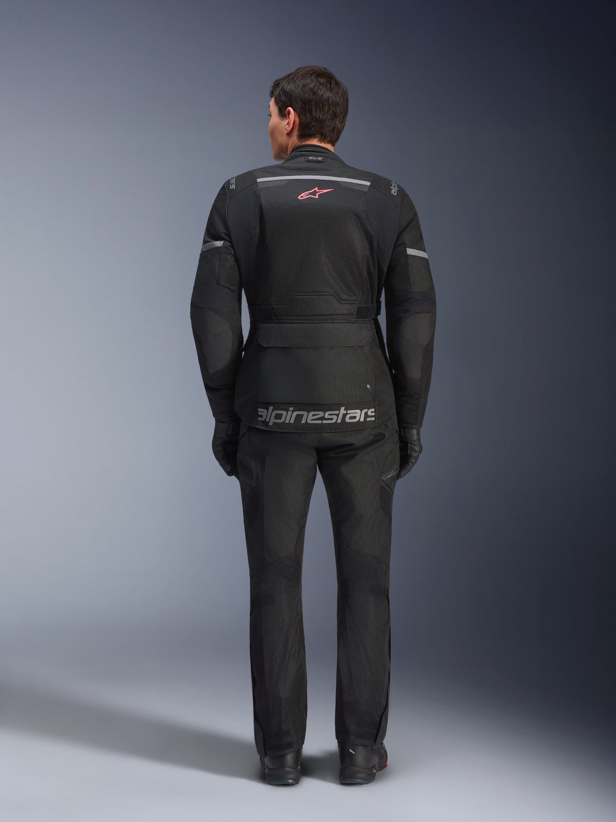 Alpinestars Andes Air Drystar® jakke og bukser, sort motorcykel touring-sæt, set bagfra, med mesh-paneler, rødt stjernelogo og reflekterende Alpinestars-branding på jakken, båret med sorte handsker og støvler.