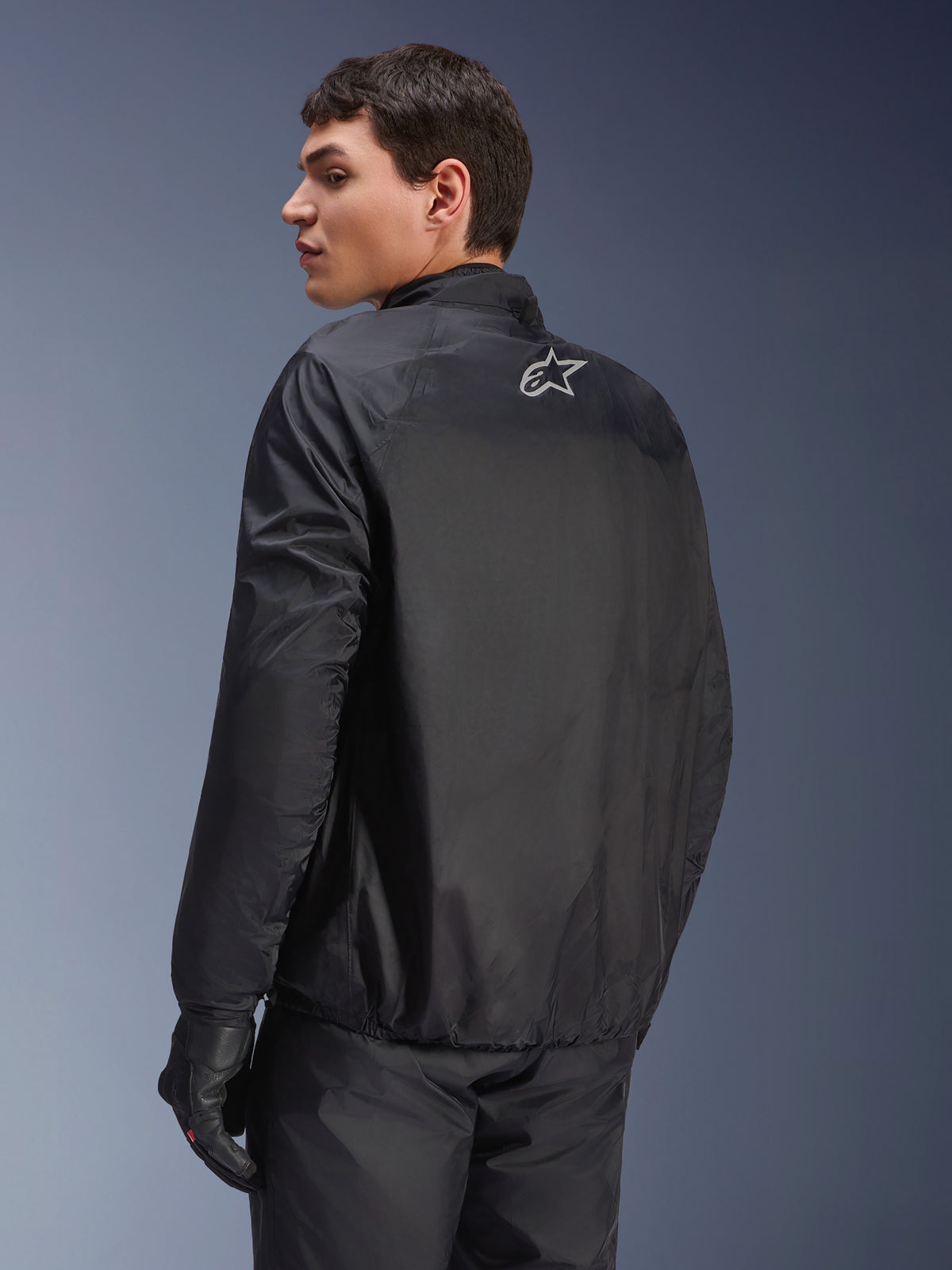 Alpinestars Andes Air Drystar®-jakke, aftagelig vandtæt membran i sort, set bagfra på en mandlig model, med et lille hvidt Alpinestars-logo øverst på ryggen, kombineret med sorte kørehandsker