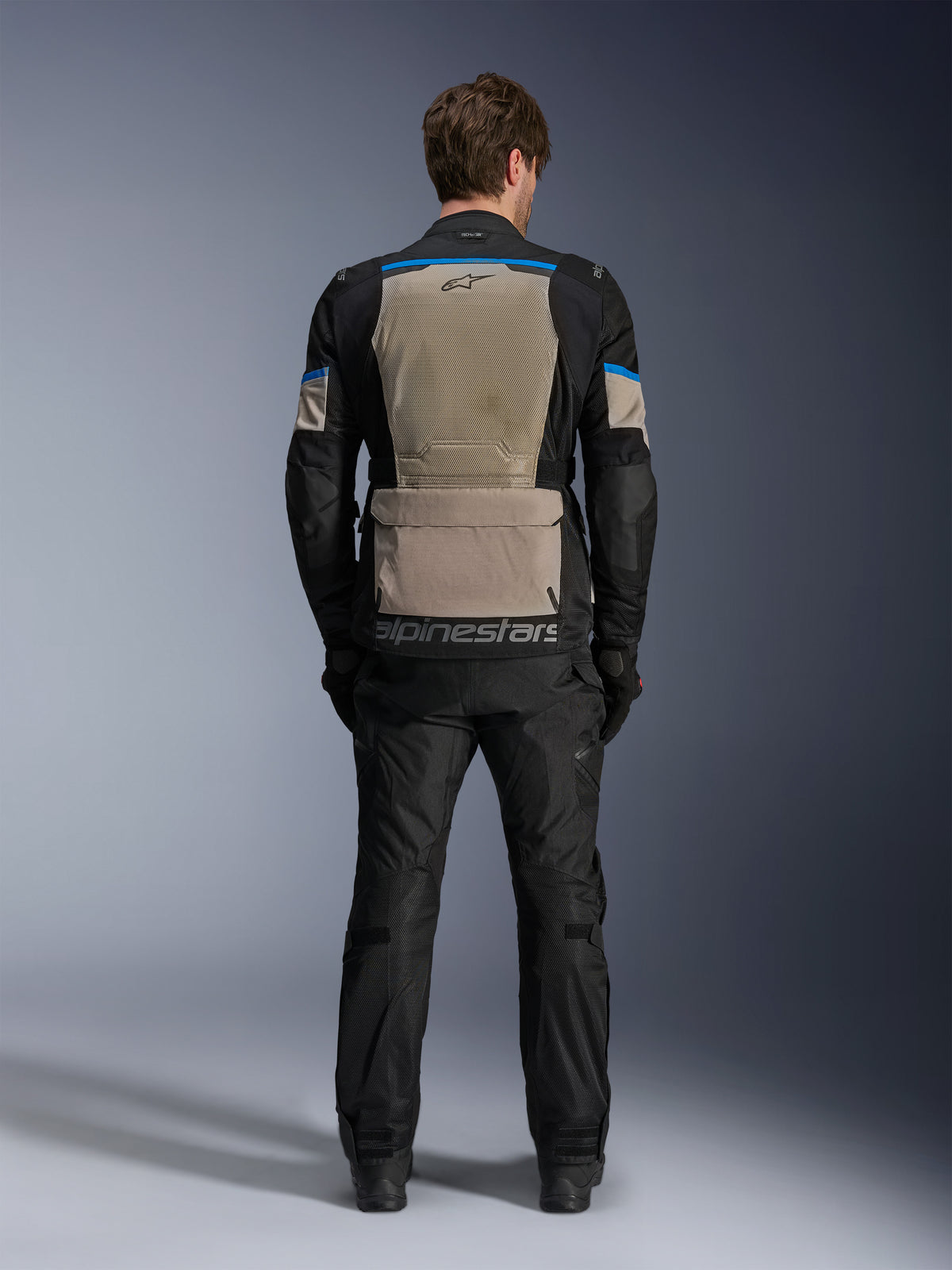Alpinestars Andes Air Drystar®-jakke, Black Laurel Gray Bright Blue, set bagfra med omfattende mesh-ventilationspanel, stor opbevaringslomme nederst på ryggen med Alpinestars-branding, teknisk motorcykel touring-jakke båret med matchende bukser.
