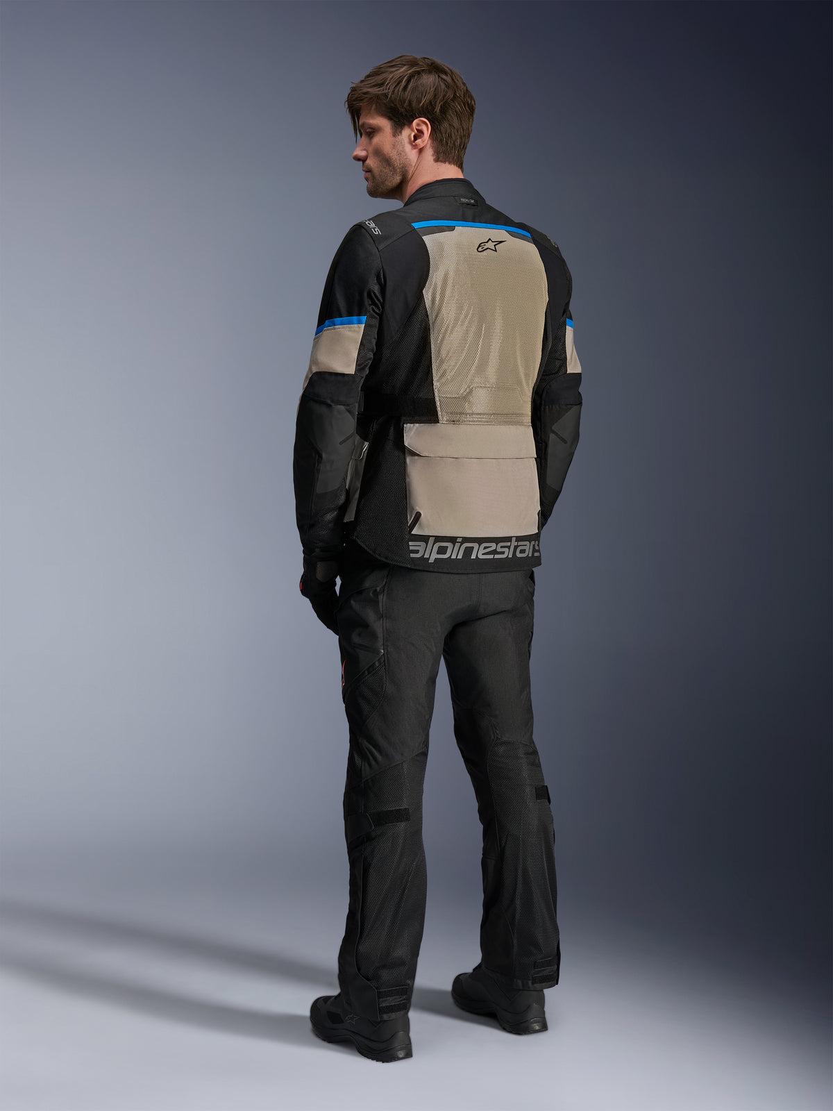 Alpinestars Andes Air Drystar® Jakke, Black Laurel Gray og Bright Blue, set bagfra viser stort mesh-ventilationspanel på ryggen, logo på den nederste kant, båret med sorte motorcykelbukser og støvler.